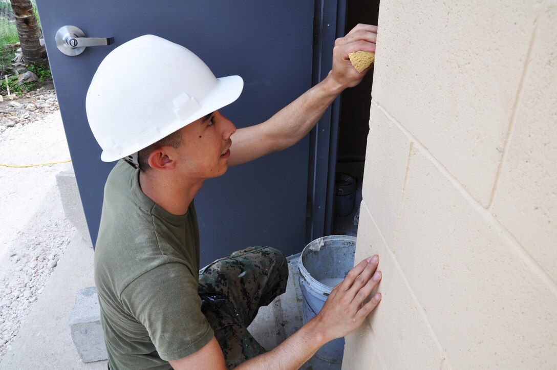 U.S. Marine Corps Sgt. Robert LaFleur, a combat engineer from Marine Wing Support Squadron 472, cleans excess caulk from the door frame at Ladyville Technical High School, May 31.  Engineers from both the U.S. and Belize are constructing various structures at schools throughout Belize as part of exercise New Horizons. (U.S. Air Force photo by Capt. Holly Hess/Released)