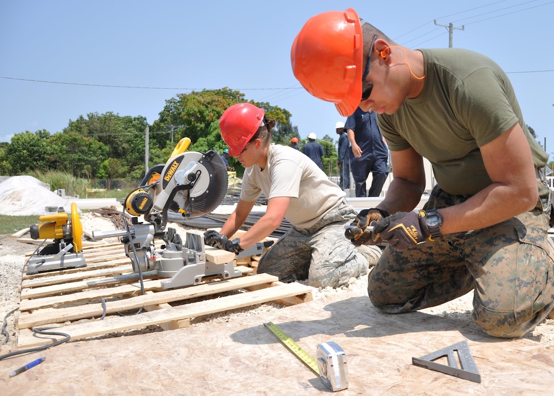 U.S. Marine Corps Lance Cpl. Joshua Rivera-Watson (Right), a combat engineer from Marine Wing Support Squadron 472, and U.S. Air Force Staff Sgt. Jenna Rogers, a medical technician from 823rd RED HORSE Squadron, cut wood to use at the construction site of Ladyville Technical High School.  Engineers from both the U.S. and Belize are constructing various structures at schools throughout Belize as part of exercise New Horizons. (U.S. Air Force photo by Capt. Holly Hess/Released)