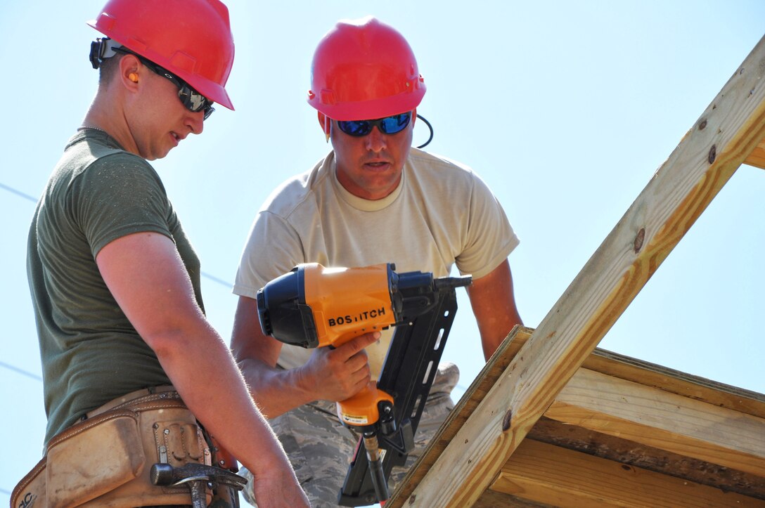 U.S. Air Force Master Sgt. Brian Barnes, structures supervisor from the 556th RED HORSE Squadron, installs roof decking with Lance Cpl. David Cafarelli, a combat engineer from Marine Wing Support Squadron 472, at Ladyville Technical High School, May 14.  Engineers from both the U.S. and Belize are constructing various structures at schools throughout Belize as part of exercise New Horizons. (U.S. Air Force photo by Capt. Holly Hess/Released)