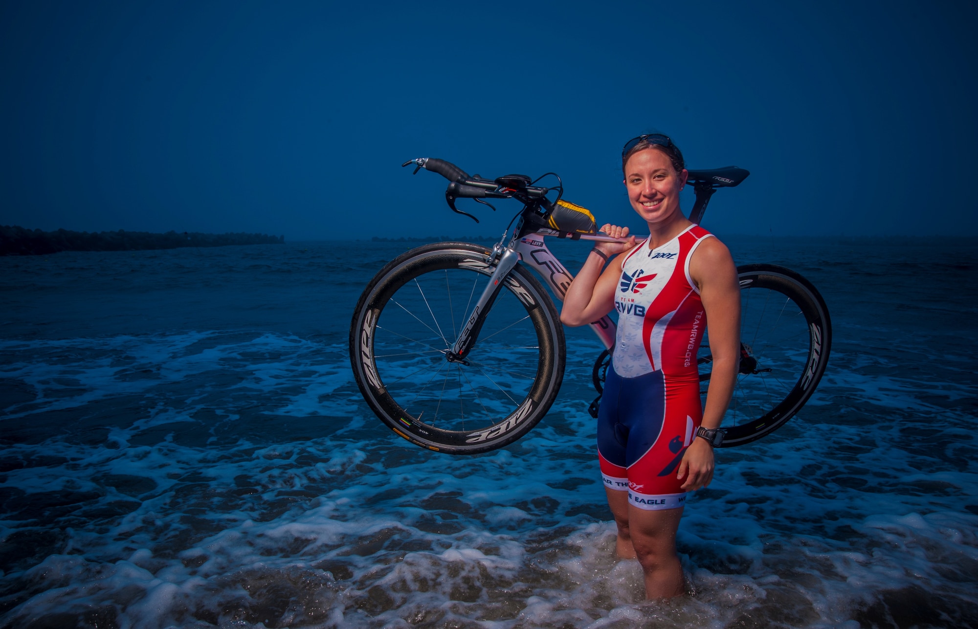Capt. Hila Levy, 35th Operations Support Squadron, poses with her triathlon racing bike in the Pacific Ocean at Miss Veedol Beach, Japan, July 25, 2013. Levy qualified to compete in the 2013 Ironman World Championships on Oct. 12 in Kailua-Kona, Hawaii – a grueling triathlon made up of a 2.4-mile rough water swim, 112 miles of bike racing and a 26.2-mile marathon. (U.S. Air Force photo/Senior Airman Derek VanHorn)