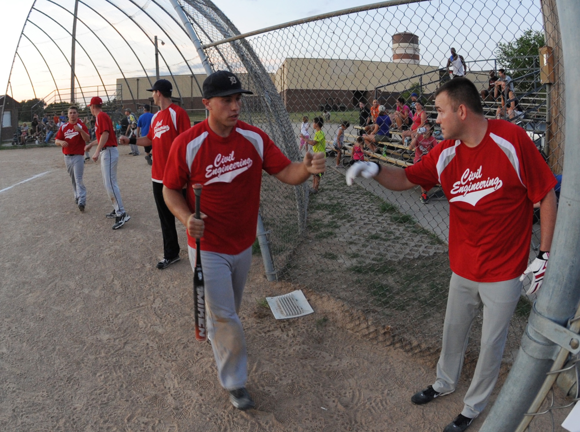 Delray Moore and Breyden Gardner, Civil Engineering team members, are congratulated by teamates after scoring runs against the Security Forces-A team at Whiteman Air Force Base, Mo., July 22, 2013.  The game concluded after six innings because of the 10-run rule stating any team winning by 10 or more runs after five innings automatically wins the game. (U.S. Air Force photo by Airman 1st Class Bryan Crane/Released)