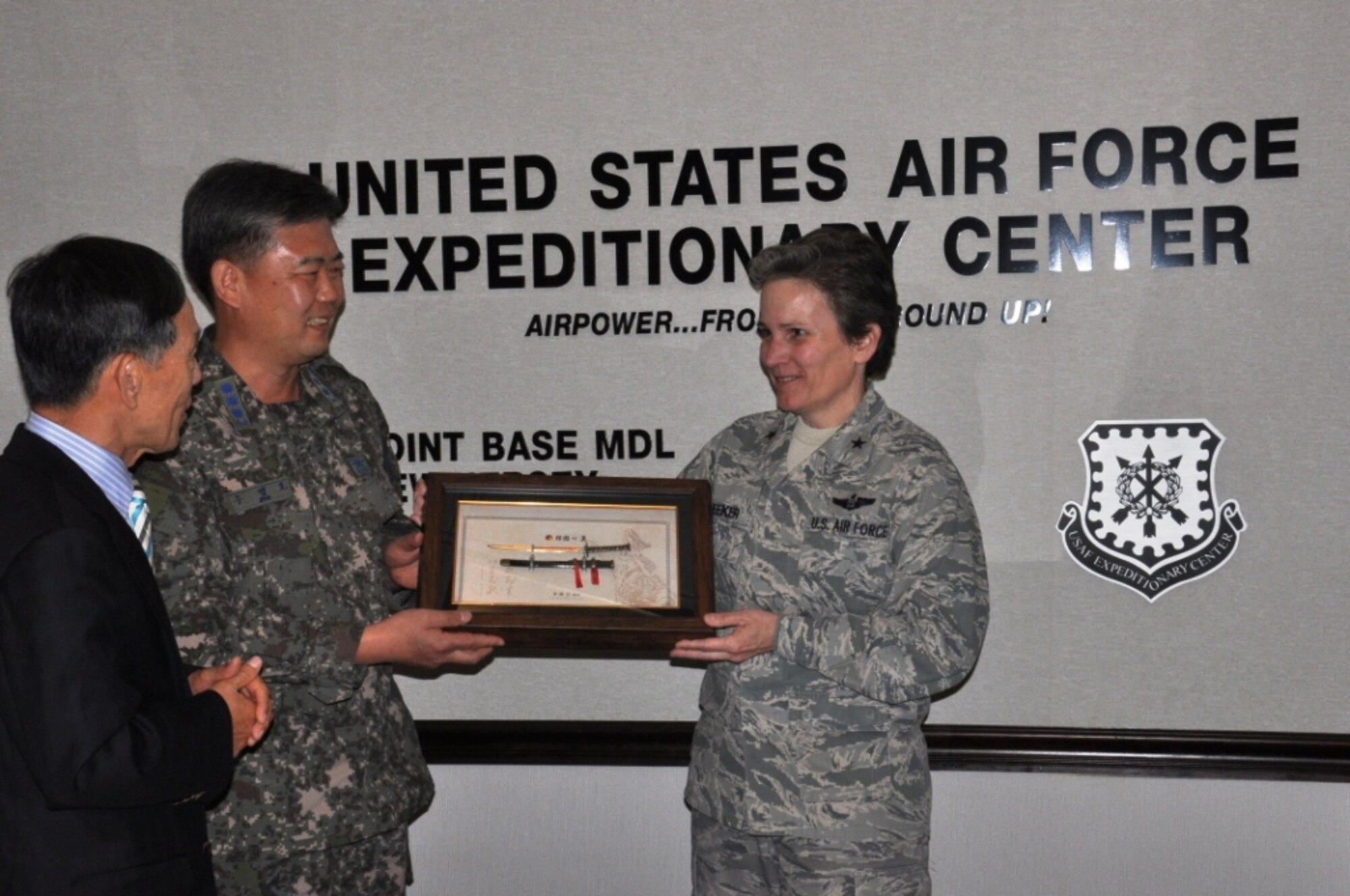 Col. Woo MaengHo and Dr. Hyon-Sang Yu, of the Republic of Korea, present Brig. Gen. Martha Meeker, U.S. Air Force Expeditionary Center vice commander, with a gift during a visit to the Center, July 12. Col. MaengHo explained the significance of the gift as a symbol providing protection for the men and women of the Expeditionary Center. The tour of the EC was part of a larger visit with various Air Force units located at Joint Base McGuire-Dix-Lakehurst, N.J. (U.S. Air Force Photo by Capt. Sybil Taunton/Released)