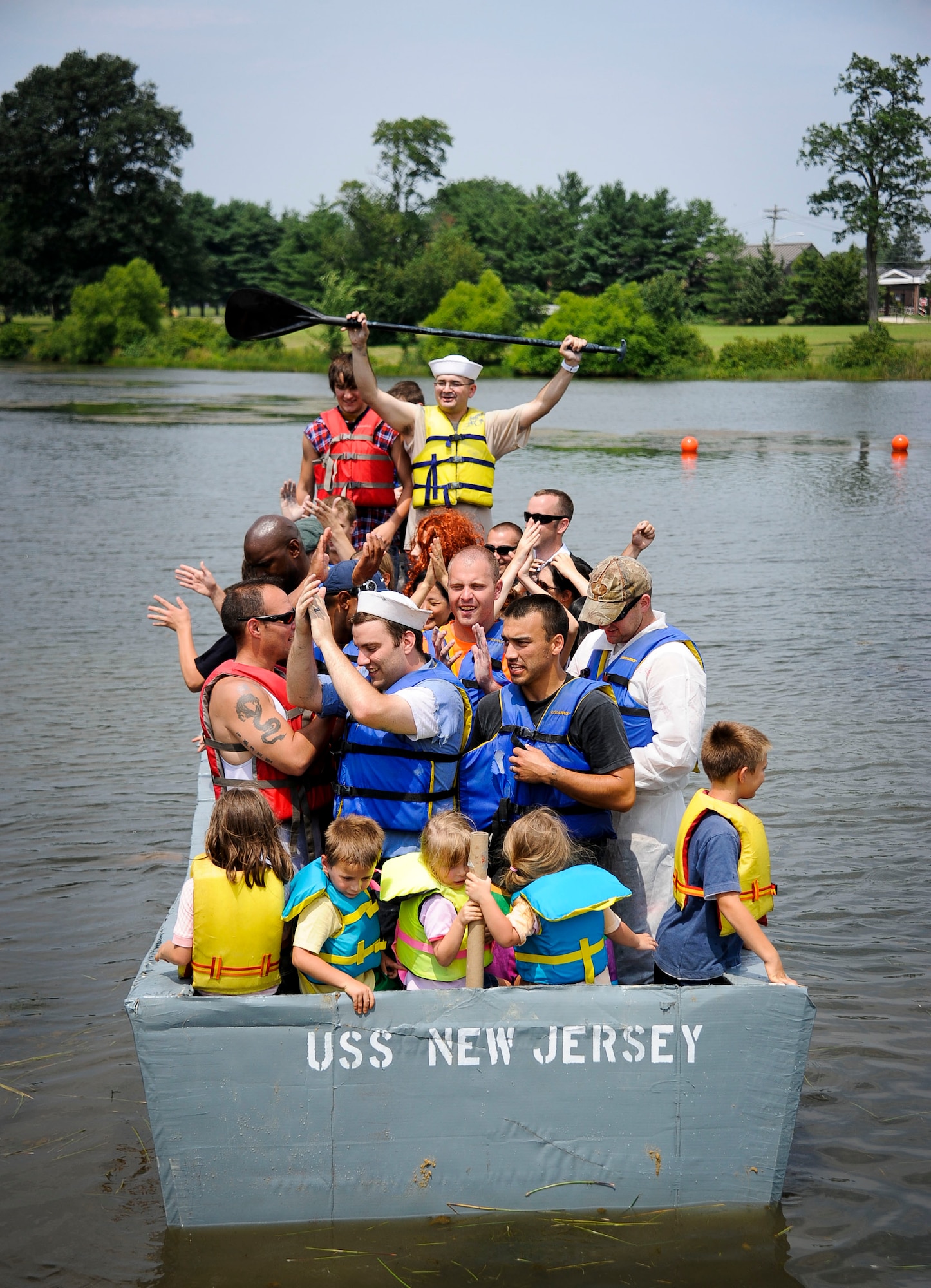 Joint base community members pile on the 305th Operations Support Squadron USS New Jersey after the second annual Cardboard Boat Regatta at Willow Pond July 20, 2013, at Joint Base McGuire-Dix-Lakehurst, N.J. The Sailors set the precedent last year by fitting 26 people on the USS Constitution. This year, they managed to fit 35. (U.S. Air Force photo by Airman 1st Class Ryan Throneberry/Released)

