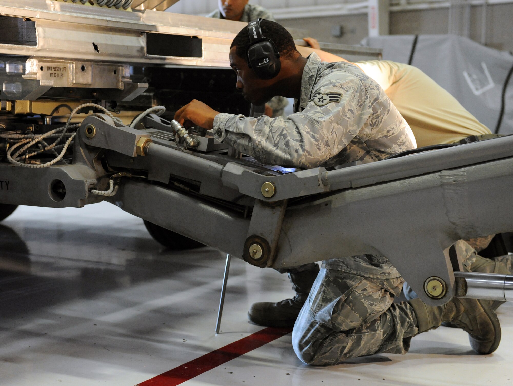 Senior Airman Keandre Lowe, 13th Aircraft Maintenance Unit load crew member, guides a jammer into position under a practice munition during a load crew of the quarter competition at Whiteman Air Force Base, Mo., July 18, 2013. The Airmen must work quickly but efficiently to showcase their loading skills. (U.S. Air Force photo by Airman 1st Class Shelby R. Orozco/Released)