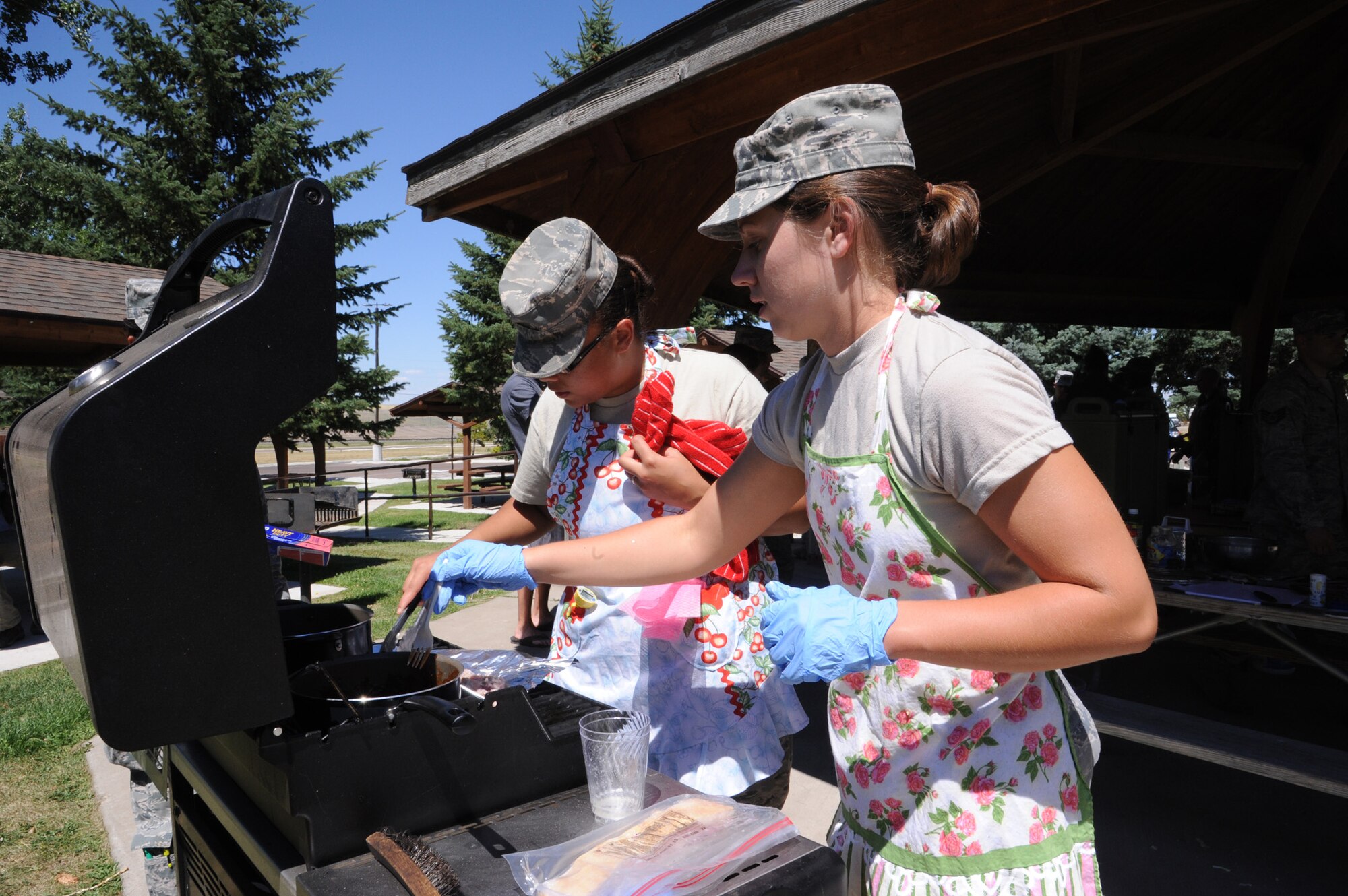 Senior Airman Brittany Booker, 341st Force Support Squadron food service journeyman, left, and Airman 1st Class Casey Bennett, 341st FSS food service apprentice, prepare barbecue sauce to go along with their miniature pork sliders and apple fries at Sun Plaza Park on July 19. Booker and Bennett, first-time competitors, won Third Quarter Warrior Chef Competition. (U.S. Air Force photo/Senior Airman Katrina Heikkinen)