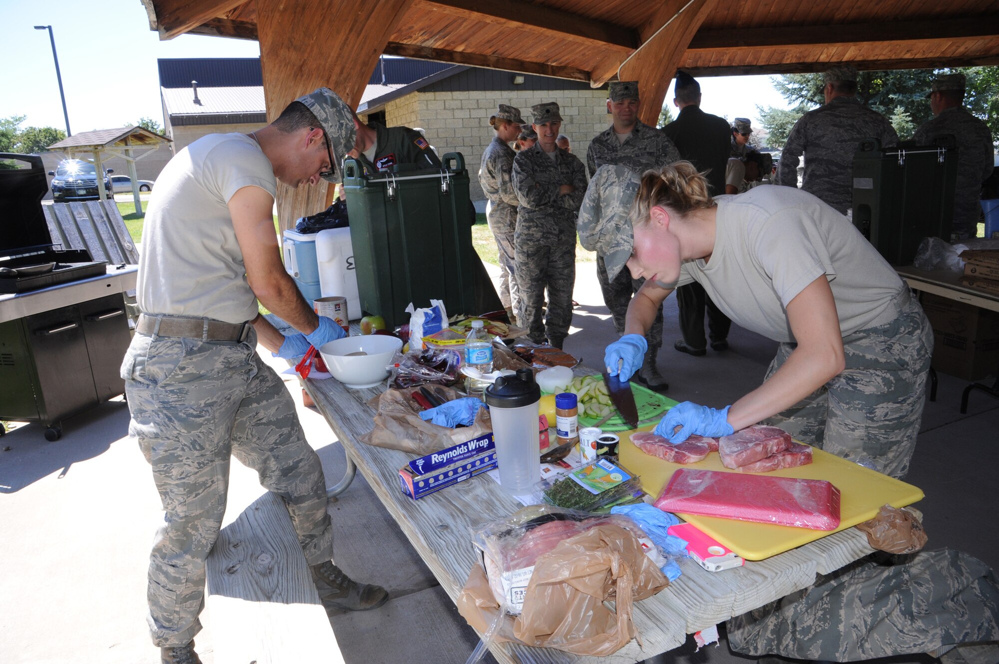 Senior Airman Adam Weaver and Airman 1st Class Gina Douglas, 12th Missile Squadron chefs, prepare stuffed pork chops and apples and onions to go along with apple cherry crisp, during the Third Quarter Warrior Chef Competition at Sun Plaza Park on July 19. The secret ingredient for the competition was apple. (U.S. Air Force photo/Senior Airman Katrina Heikkinen) 