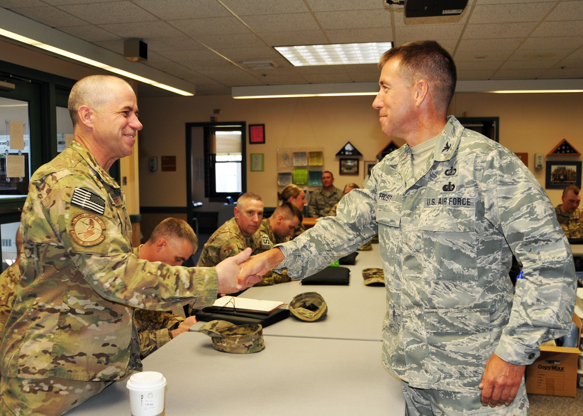 Col. Troy Frost, 120th Fighter Wing Support Group commander, presents his coin to Senior Master Sgt. Kurt Trowbridge, 120th Security Forces Squadron member, in recognition of completing a six-month overseas deployment in support of Operation Enduring Freedom.  Trowbridge and 13 other Airmen were beginning their in-processing activities on July 16. (U.S. Air Force photo/Senior Master Sgt. Eric Peterson)