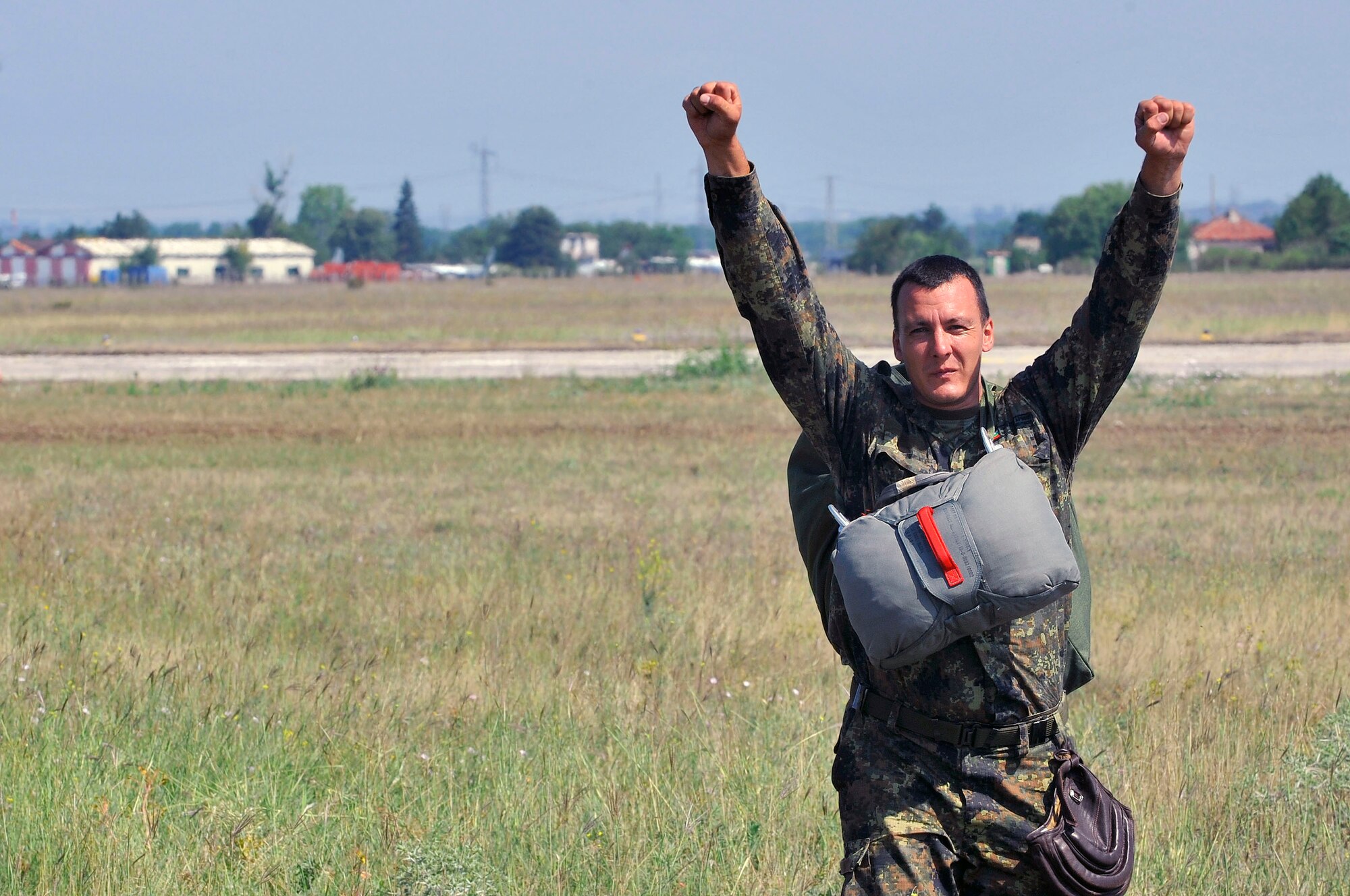 A Bulgarian paratrooper celebrates after landing from a wing exchange jump, where he used the American parachute, July 17, 2013, Plovdiv, Bulgaria. American and Bulgarian paratroopers exchanged parachutes for the opportunity to conduct a wing exchange at the end of Thracian Summer. (U.S. Air Force photo/Airman 1st Class Trevor Rhynes)
