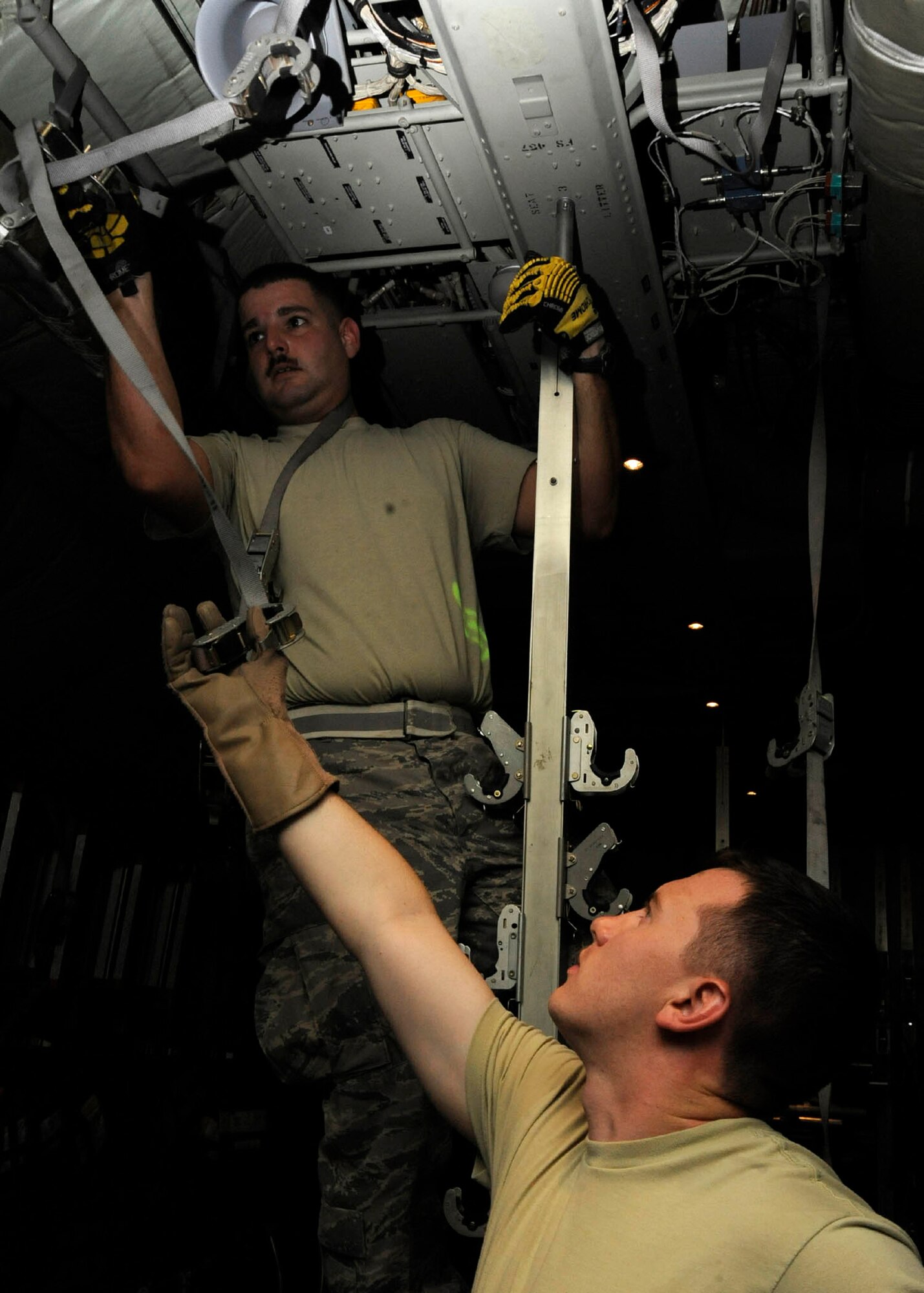 Tech. Sgt. Chris Hines passes a hanging trap to Senior Airman Christopher Roland while prepping a C-130 for an aeromedical evacuation mission at the 379th Air Expeditionary Wing in Southwest Asia, July 24, 2013. Hines and Roland are 379th Expeditionary Aeromedical Evacuation Squadron aeromedical evacuation technicians deployed from Maxwell Air Force Base, Ala., and Kadena Air Base, Japan, respectively. (U.S. Air Force photo/Senior Airman Bahja J. Jones) 