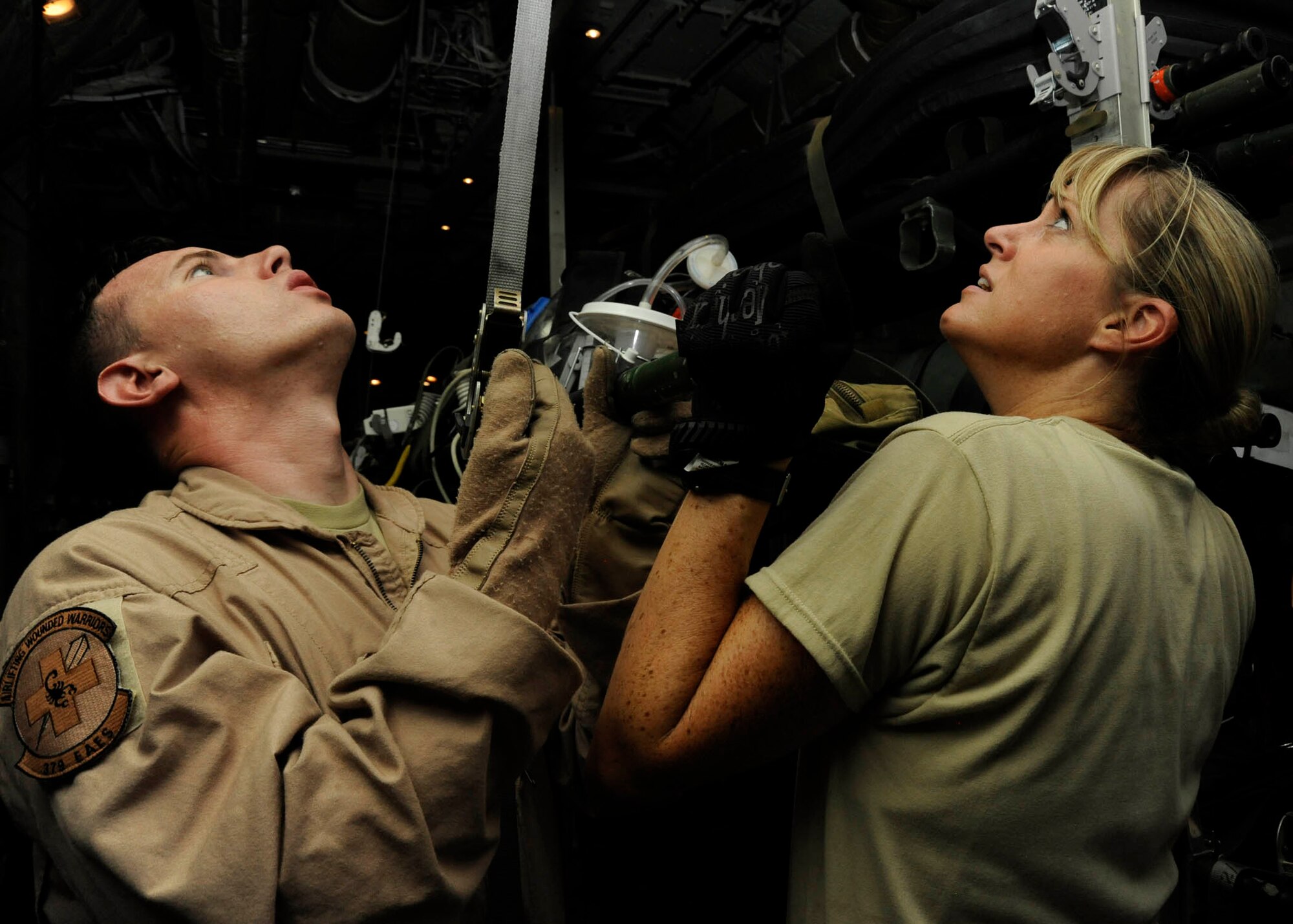 Senior Airman Christopher Roland and Tech. Sgt. Angela Burton secure a litter into a hanging strap on a C-130 Hercules in preparation for an aeromedical evacuation mission at the 379th Air Expeditionary Wing in Southwest Asia, July 24, 2013. Roland and Burton are 379th Expeditionary Aeromedical Evacuation Squadron aeromedical evacuation technicians deployed from Kadena Air Base, Japan, and Maxwell Air Force Base, Ala., respectively. (U.S. Air Force photo/Senior Airman Bahja J. Jones) 