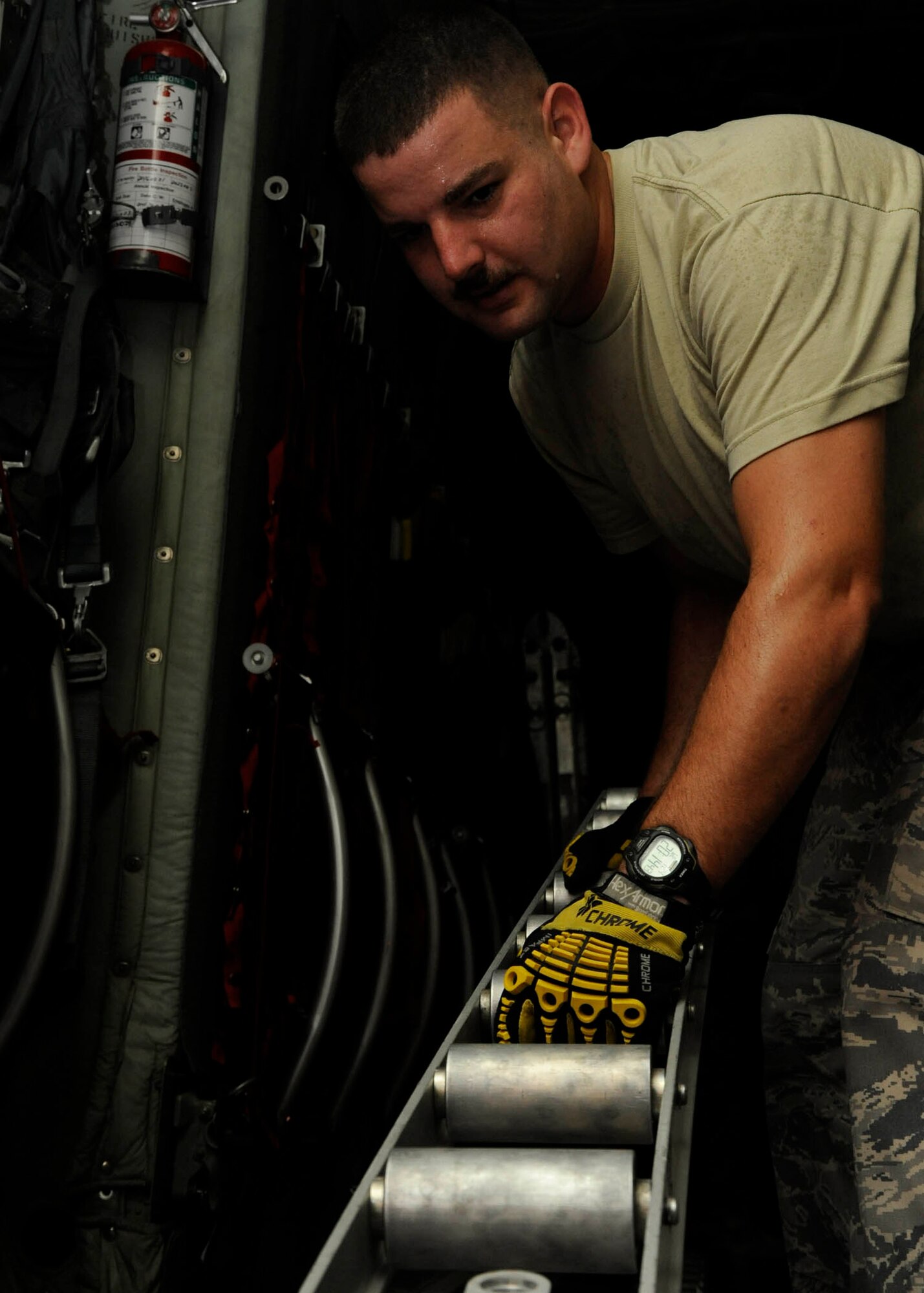 Tech. Sgt. Chris Hines moves rollers to the side of a C-130 Hercules while prepping for an aeromedical evacuation mission at the 379th Air Expeditionary Wing in Southwest Asia, July 24, 2013. Hines is a 379th Expeditionary Aeromedical Evacuation Squadron aeromedical evacuation technician deployed from Maxwell Air Force Base, Ala. (U.S. Air Force photo/Senior Airman Bahja J. Jones) 