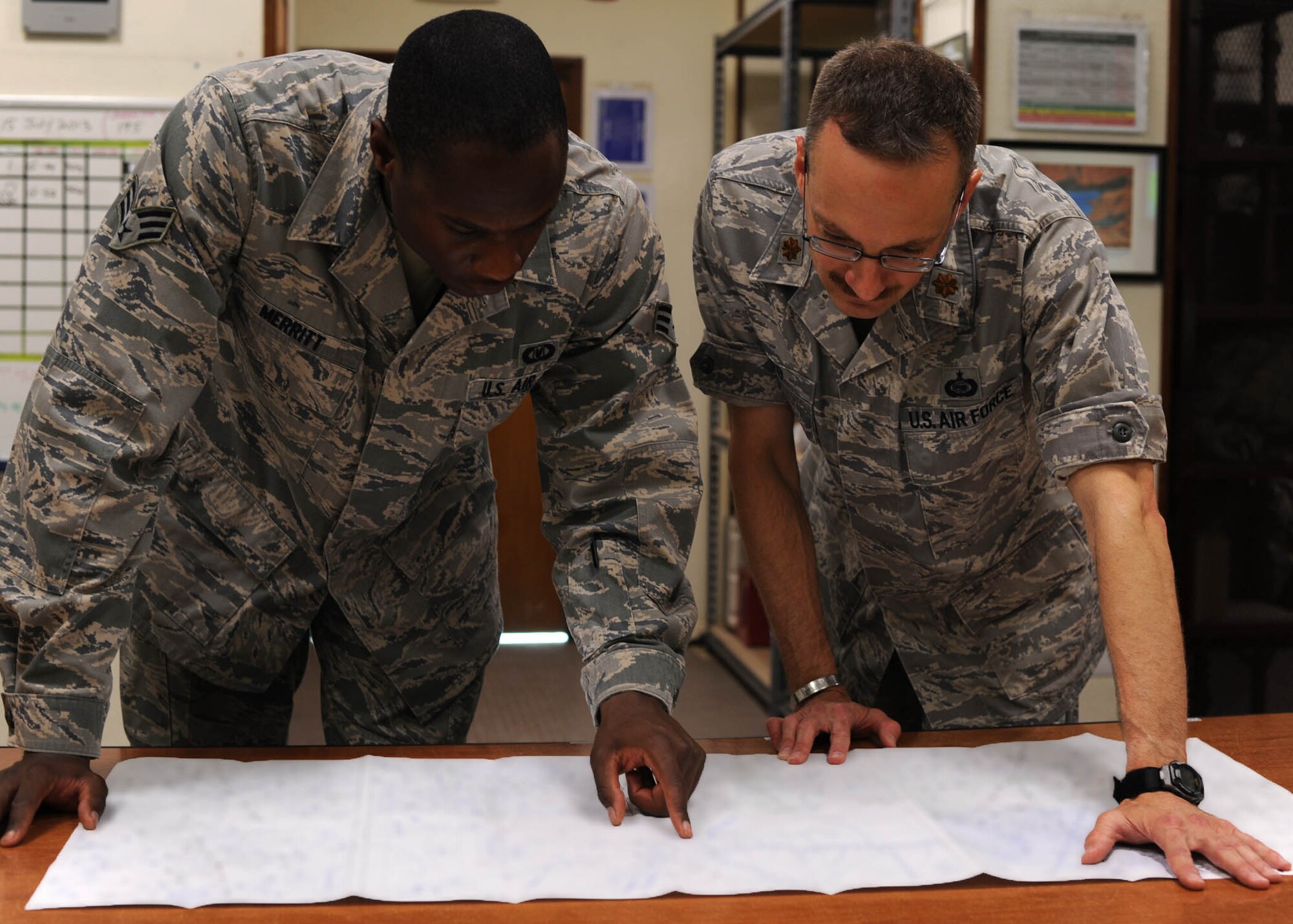 Maj. Michael Korb and Senior Airman Kevin Merritt review survival information for an upcoming C-130 Hercules mission at the 379th Air Expeditionary Wing in Southwest Asia, July 15, 2013. Korb is the 746th Expeditionary Airlift Squadron Intel chief and Merritt is a 379th Expeditionary Operations Support Squadron aircrew flight equipment technician. Both are deployed from Peterson Air Force Base, Colo. (U.S. Air Force photo/Senior Airman Bahja J. Jones) 