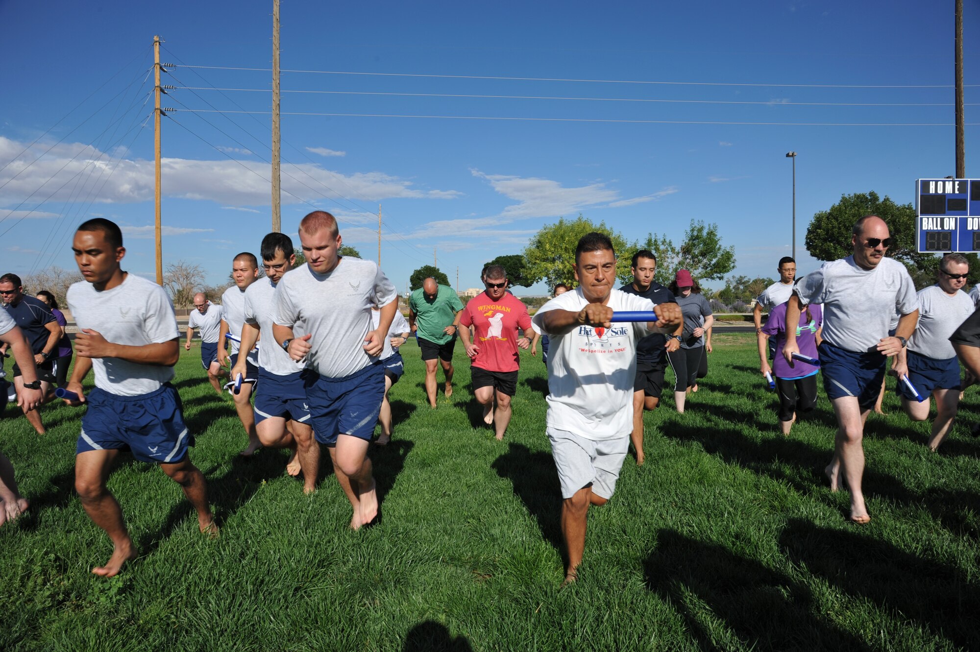 Participants of the running clinic, hosted by the Health and Wellness Center, practice shortening strides, lifting their legs rather than pushing off with their feet, and bending their elbows to relax breathing and movements, all while running barefoot.  (Photo by Ken Moore)