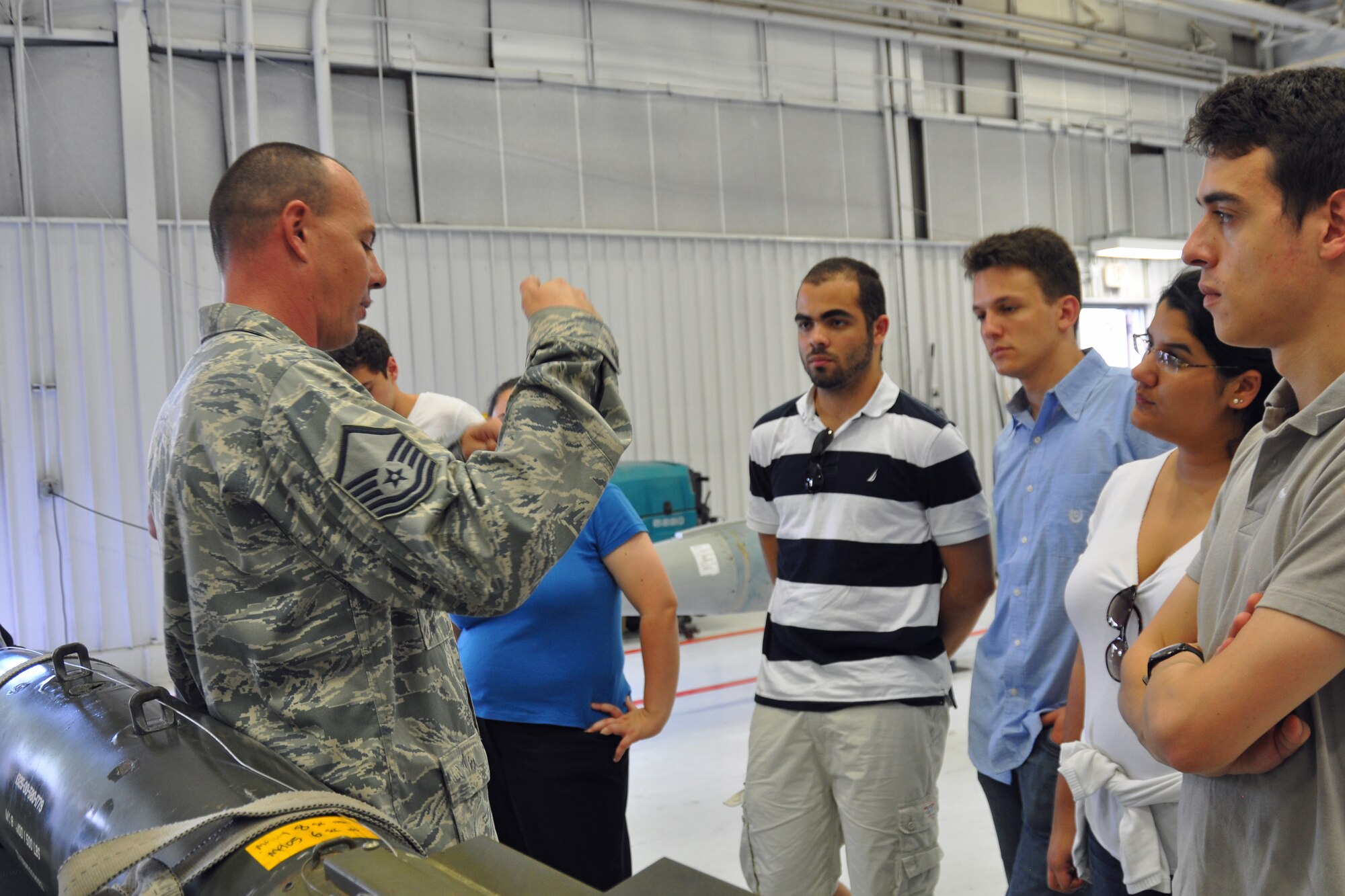 Graduate and doctoral engineering students from Brazil discuss the Joint Direct Attack Munition GBU-38 bomb with Master Sgt. Christopher Rasco, a load standardization team chief assigned to the 355th Maintenance Operations Squadron, at Davis-Monthan Air Force Base, July 24. The students were in Tucson, Ariz., visiting the nearby Raytheon Company as part of Brazil’s Science Without Borders program and requested the opportunity to visit D-M.  The GBU-38 is the smallest version of the JDAM weighing in at approximately 500 pounds. (U.S. Air Force photo/Capt. Jonathan Simmons)