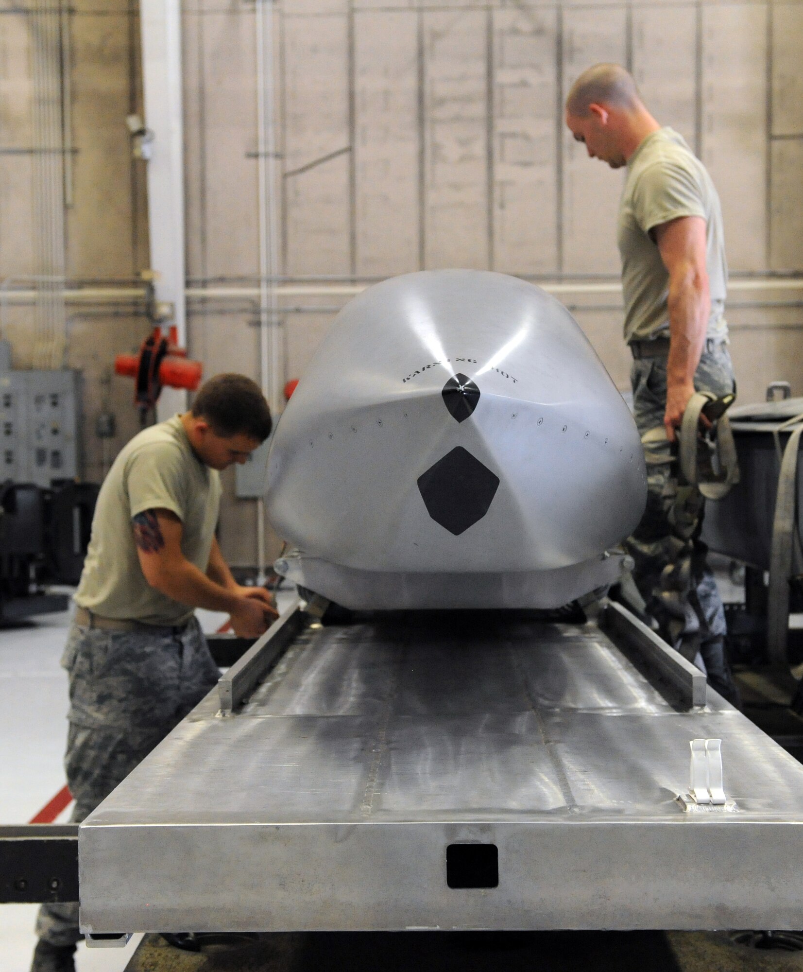 Airmen 1st Class Daniel Villarreal and Ryan Lose, 393rd Aircraft Maintenance Unit load crew members, prepare a practice munition for loading onto a mock B-2 Spirit stealth bomber weapons bay during a load crew competition at Whiteman Air Force Base, Mo., July 18, 2013. These quarterly competitions help the Airmen maintain their mission-readiness, ensuring they can do their job at a moment’s notice. (U.S. Air Force photo by Airman 1st Class Shelby R. Orozco/Released)