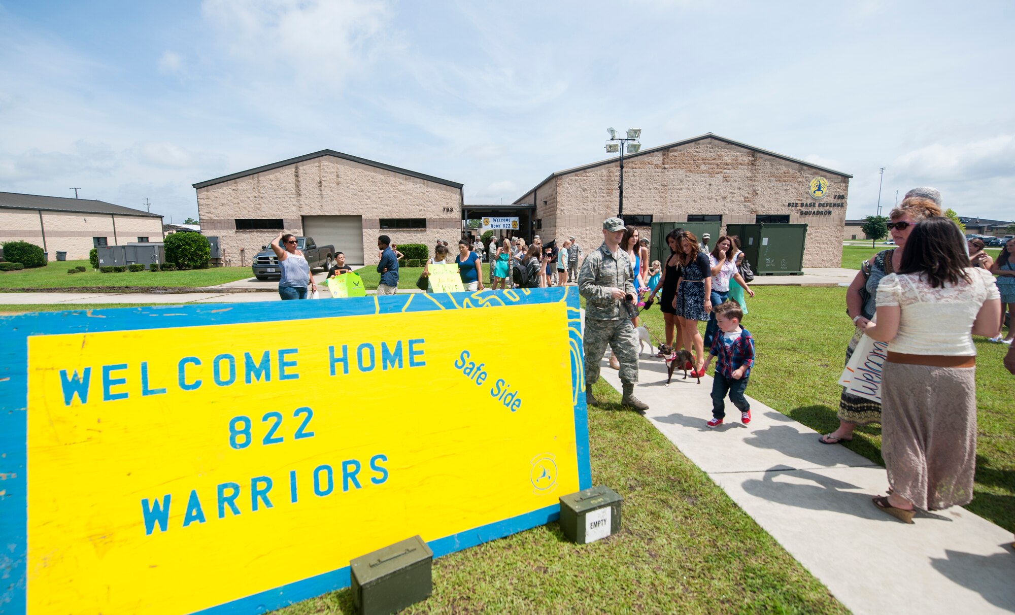 Friends and family gather around a welcome-home sign during an 822nd Base Defense Squadron deployment return at Moody Air Force Base, Ga., July 24, 2013. Approximately 110 Airmen from the 822nd BDS and 30 Airmen from the New York Air National Guard’s 105th Security Forces Squadron deployed together in December 2012. (U.S. Air Force photo by Senior Airman Jarrod Grammel/Released)
