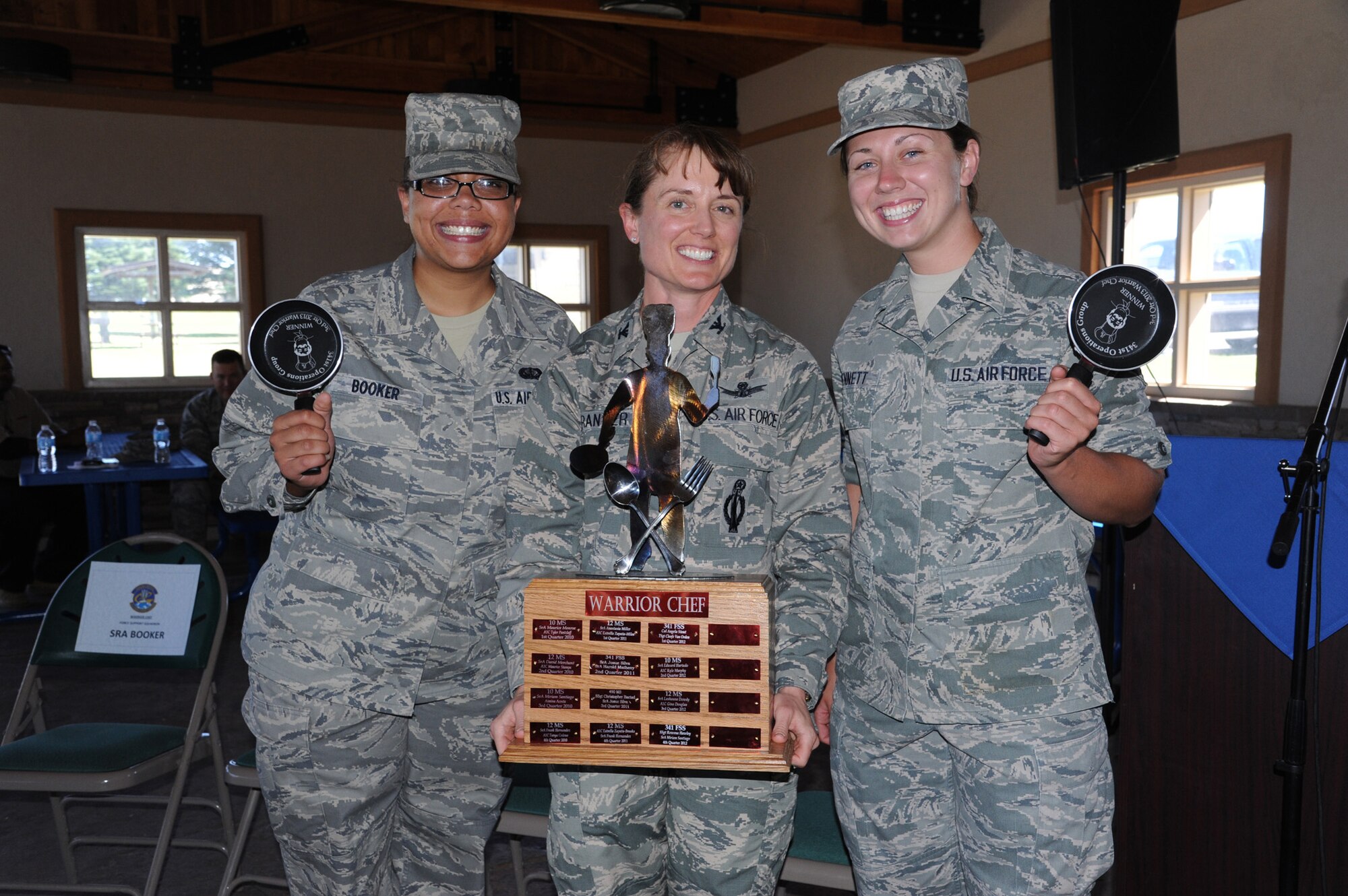 Col. Marné Deranger, 341st Missile Wing vice commander, center, presents the Warrior Chef trophy to the winners of the quarterly challenge, Senior Airman Brittany Booker, 341st Force Support Squadron food service journeyman, left, and Airman 1st Class Casey Bennett, 341st FSS food service apprentice, at Sun Plaza Park on July 19. The two competitors will have their name engraved on the coveted Warrior Chef trophy as 2013’s Third Quarter Warrior Chef Competition Winners. (U.S. Air Force photo/Senior Airman Katrina Heikkinen)