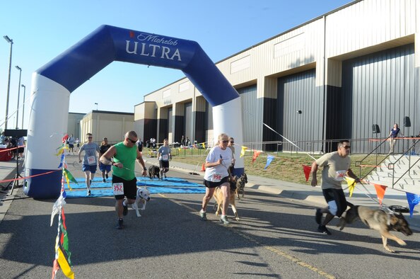 Participants of the 2K Dog ‘n Jog event take off from the start line with their four-legged friends in hand during the Second Annual Striker Life Half Marathon at the Fitness Center on July 20. Prizes for the winners of all the events included a race shirt, gift cards, cash prize, medal and a doggie bag for the 2K Dog ‘N’ Jog participants. (U.S. Air Force photo/Airman 1st Class Collin Schmidt)
