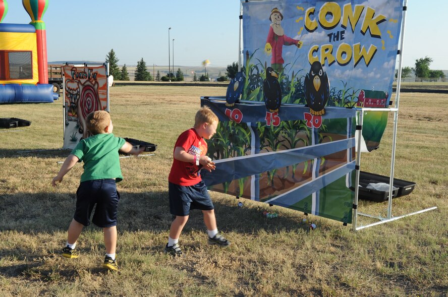 Josh and Caleb Conklin try to win a prize for knocking down the crows at a fun booth set up during the Second Annual Striker Life Half Marathon outside the Fitness Center on July 20. The marathon festivities included several other activities for children to enjoy including two bounce castles.  (U.S. Air Force photo/Airman 1st Class Collin Schmidt)