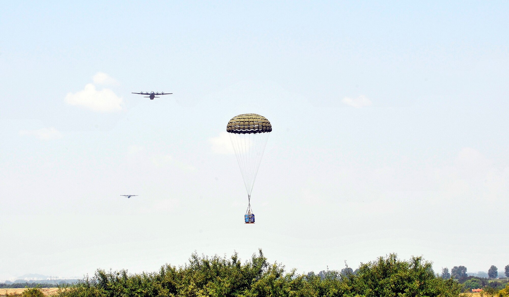 A container deployment system floats to the ground as two C-130J Super Hercules aircraft prepare to drop their CDS bundles during a flying training deployment, July 16th, 2013, Plovdiv, Bulgaria. FTD Thracian Summer is an opportunity for American and Bulgarian forces to train together and learn how each other perform their mission. (U.S. Air Force photo/Airman 1st Class Trevor Rhynes) 