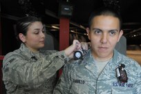 Airman 1st Class Nicolette Sanchez, 359th Medical Group Aerospace and Operational  Physiology  Squadron bioenvironmental engineering journeyman, places an air sampling media in the breathing zone of Senior Airman Homero Carrillo, 902nd Security Forces Squadron combat arms instructor, July 18 at Joint Base San Antonio-Randolph. (U.S. Air Force photo by Joel Martinez)
