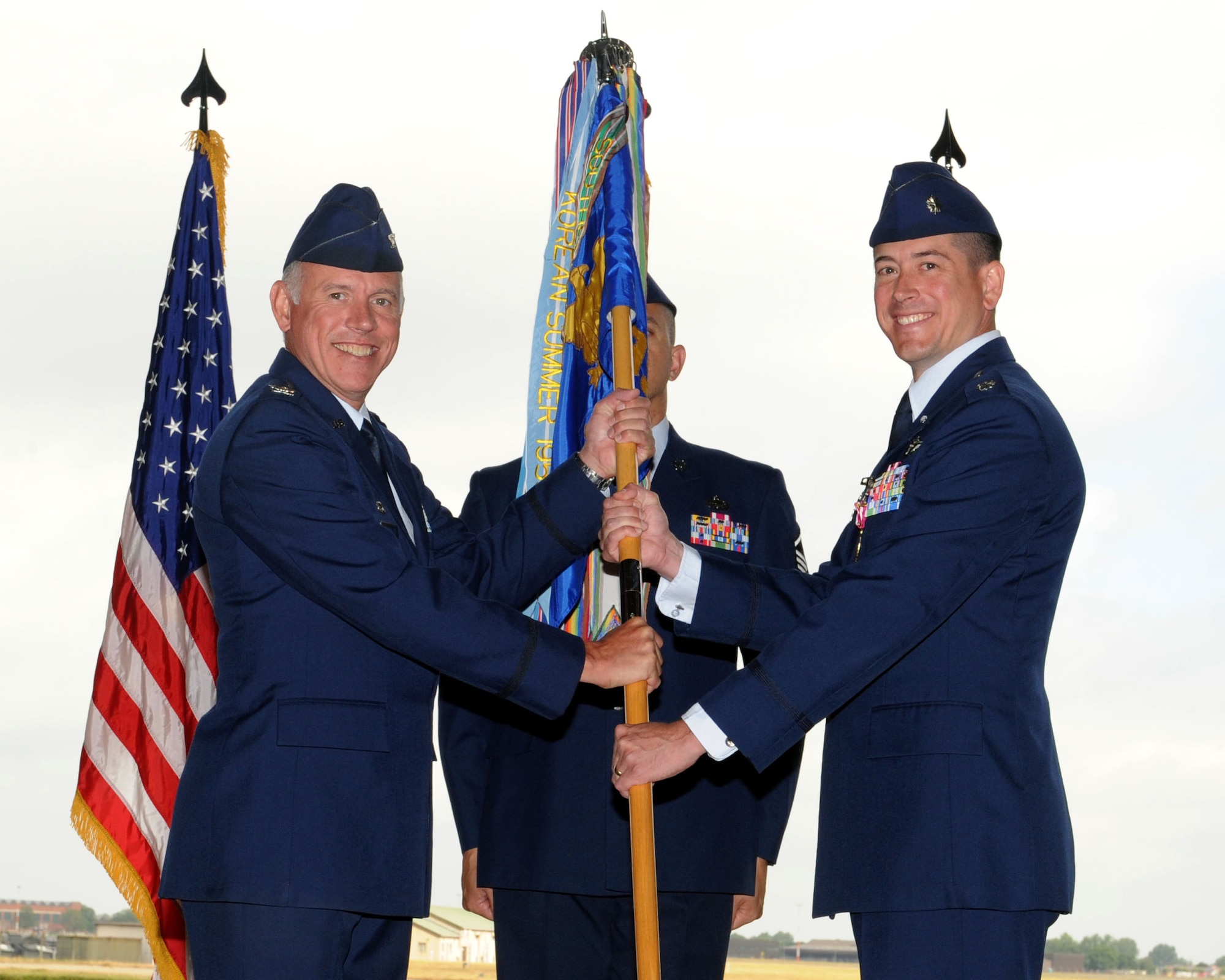From right, Lt. Col. Eric Paulson, outgoing 95th Reconnaissance Squadron, relinquishes the 95th RS guidon to Col. Russell Mammoser, 55th Operations Group commander, Offutt Air Force Base, Neb., during the 95th RS change of command ceremony July 25, 2013, on RAF Mildenhall, England. As 95th RS commander, Paulson was responsible for executing all RC-135 operations and maintenance in the European and African theaters and oversaw a detachment at Naval Support Activity Souda Bay, Crete, Greece. (U.S. Air Force photo by Airman 1st Class Preston Webb/Released)