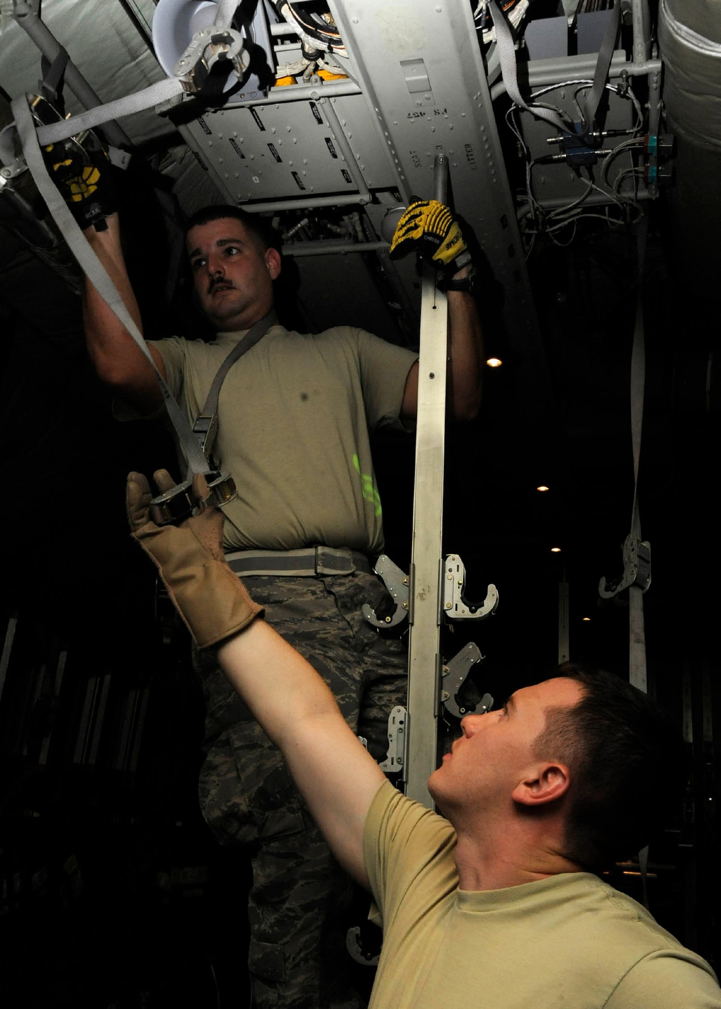 Tech. Sgt. Chris Hines passes a hanging trap to Senior Airman Christopher Roland while prepping a C-130 for an aeromedical evacuation mission at the 379th Air Expeditionary Wing in Southwest Asia, July 24, 2013. Hines and Roland are 379th Expeditionary Aeromedical Evacuation Squadron aeromedical evacuation technicians deployed from Maxwell Air Force Base, Ala., and Kadena Air Base, Japan, respectively. (U.S. Air Force photo/Senior Airman Bahja J. Jones) 