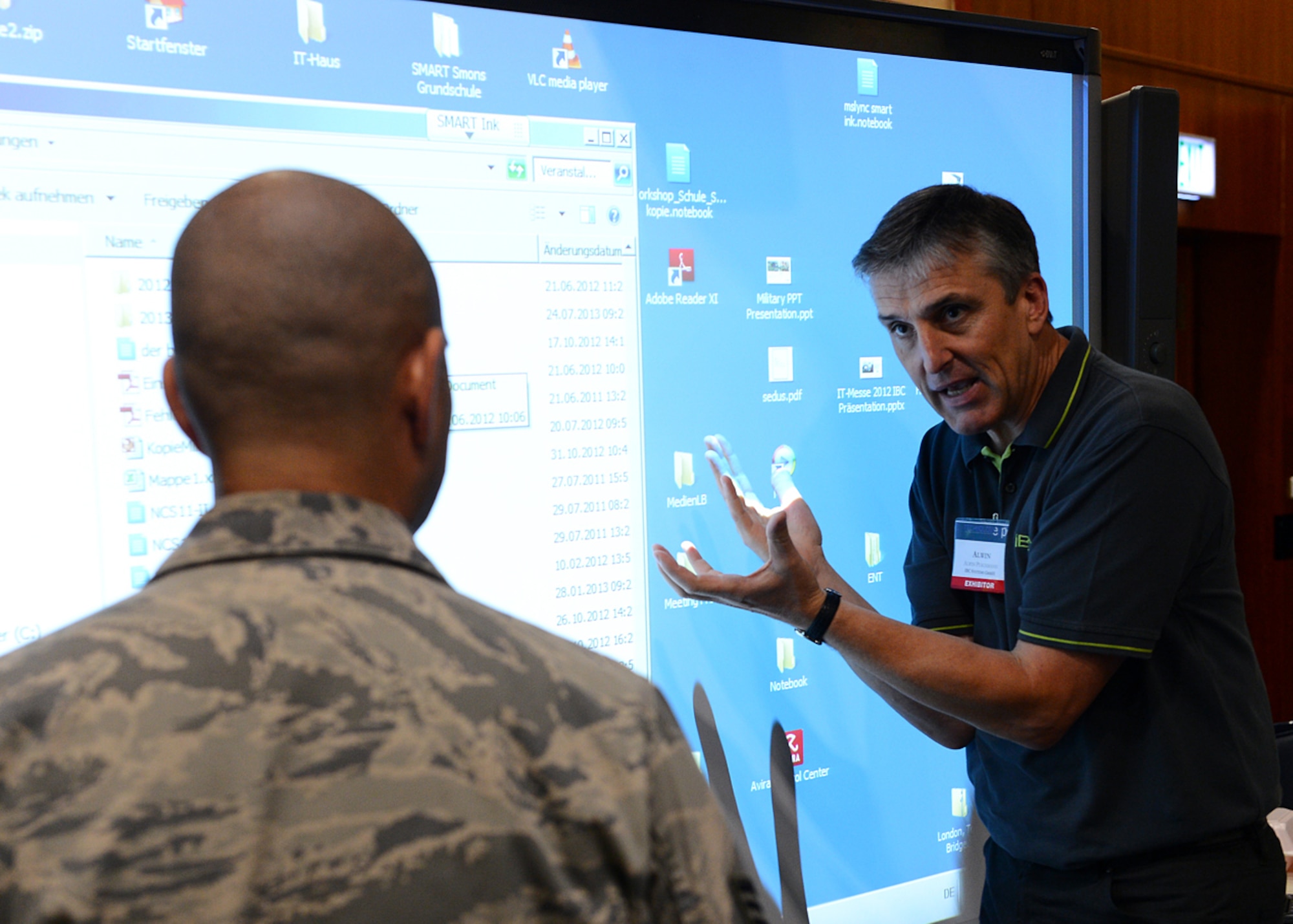 SPANGDAHLEM AIR BASE, Germany -- Alwin Puschmann, IBC Systems in Bitburg, explains how to operate an interactive whiteboard to U.S. Air Force Staff Sgt. Modesto Alcala, American Forces Network, at the 2013 Spangdahlem Technology Expo July 24, 2013. More than 25 exhibitors demonstrated their modern technology to the Spangdahlem community. The interactive whiteboard is intended for office or conference settings and uses multiple interface capabilities. (U.S. Air Force photo by Staff Sgt. Daryl Knee/Released)