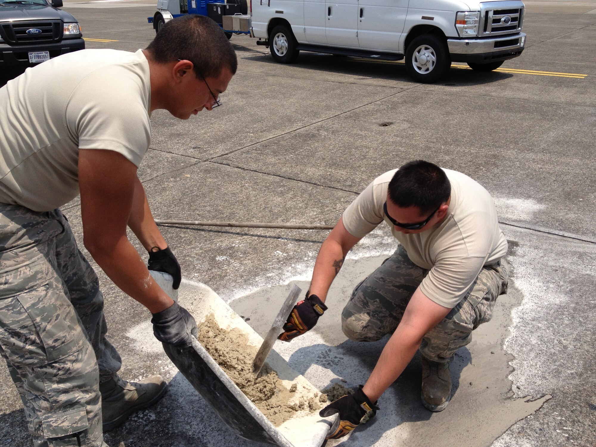 Airman 1st Class Evan Mora and Senior Airman Zakhary Jacks, 374th Civil Engineer Squadron, fill test holes in the runway July 12, 2013, at Yokota Air Base, Japan. The holes were made by an airfield pavement evaluation team sent to Yokota to determine overall airfield condition and report any needed repairs. (Courtesy photo) 