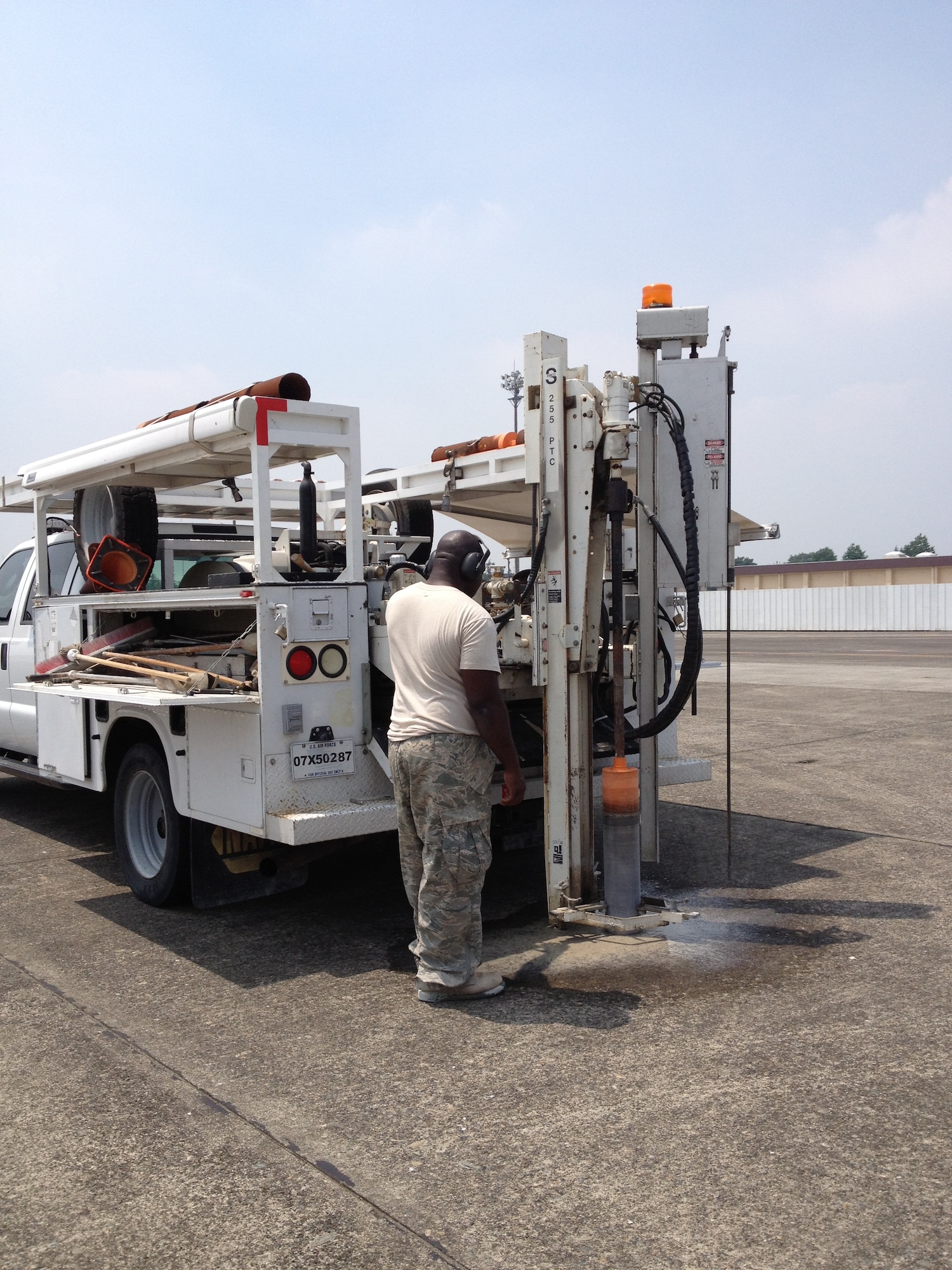 Staff Sgt. Cory Montgomery, Air Force Civil Engineer Center Airfield Pavement Evaluation team member, drills a runway-core sample July 12, 2013, at Yokota Air Base, Japan. Montgomery and his evaluation team tested the airfield conditions at Yokota to ensure it was meeting mission-ready standards and to report any needed repairs. (Courtesy photo)