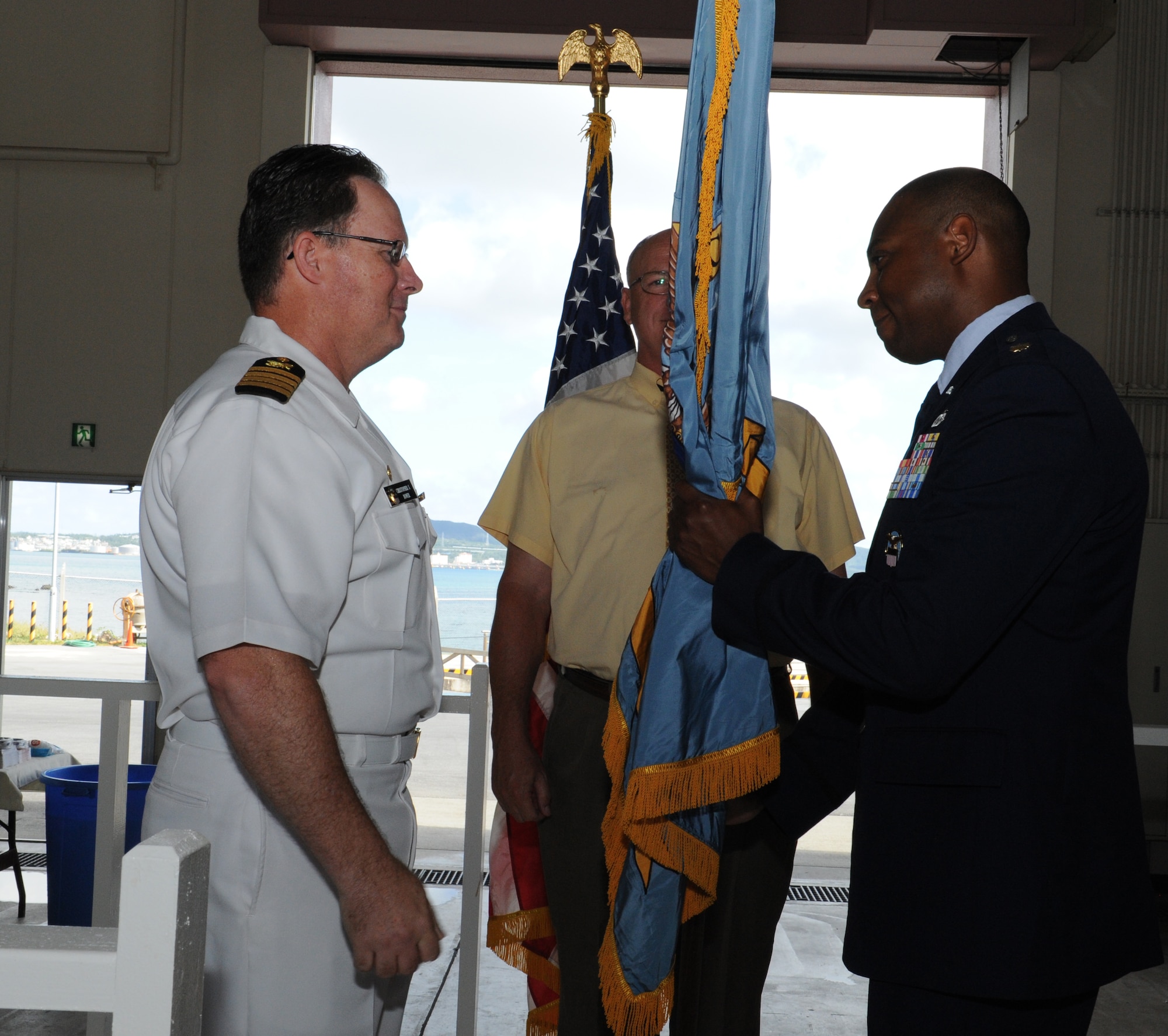 U.S. Navy Capt. Christopher Bower, Defense Logistics Agency Energy Pacific commander, presents the guidon to U.S. Air Force Maj. Andre Bradley, DLA Energy Pacific at Okinawa commander, during an assumption of command ceremony on Camp Courtney, Japan, July 25, 2013. DLA Energy Pacific at Okinawa is responsible for the operation of fuel terminals on the island and the distribution of approximately 70 million gallons of jet fuel and marine grade diesel annually. Bradley oversees the responsibilities of providing operational fuel support to all Department of Defense entities on the island. (U.S. Air Force photo by Airman 1st Class Keith A. James/Released)