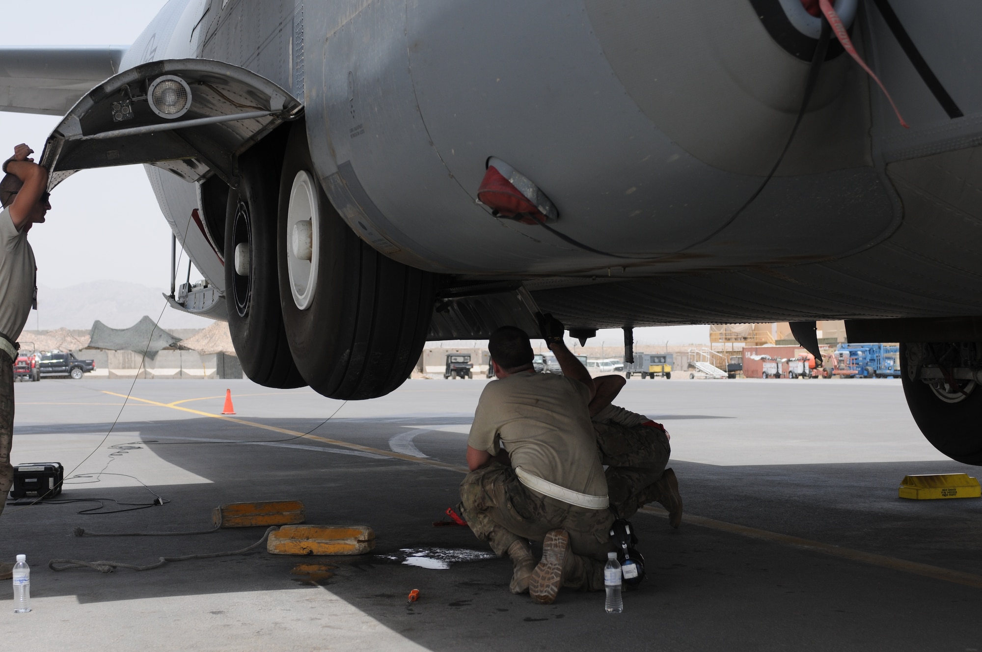 (From left) Staff Sgt. Daniel Ward, Senior Airmen Zachary Moore and Andrew Kaercher work on the brake line of a C-130J Super Hercules at Kandahar Airfield, Afghanistan, July 17, 2013. Maintainers must contend with many environmental factors while working and repairing aircraft, including intense heat and dust. The Airmen are assigned to the C-130 Aircraft Maintenance Unit of the 451st Expeditionary Aircraft Maintenance Squadron, and are deployed from Little Rock Air Force Base, Ark. Ward is a Great Falls, Mont., native, Moore is from Pickerington, Ohio, and Kaercher is from Tuscon, Ariz. (U.S. Air Force photo/Capt. Brian Maguire)