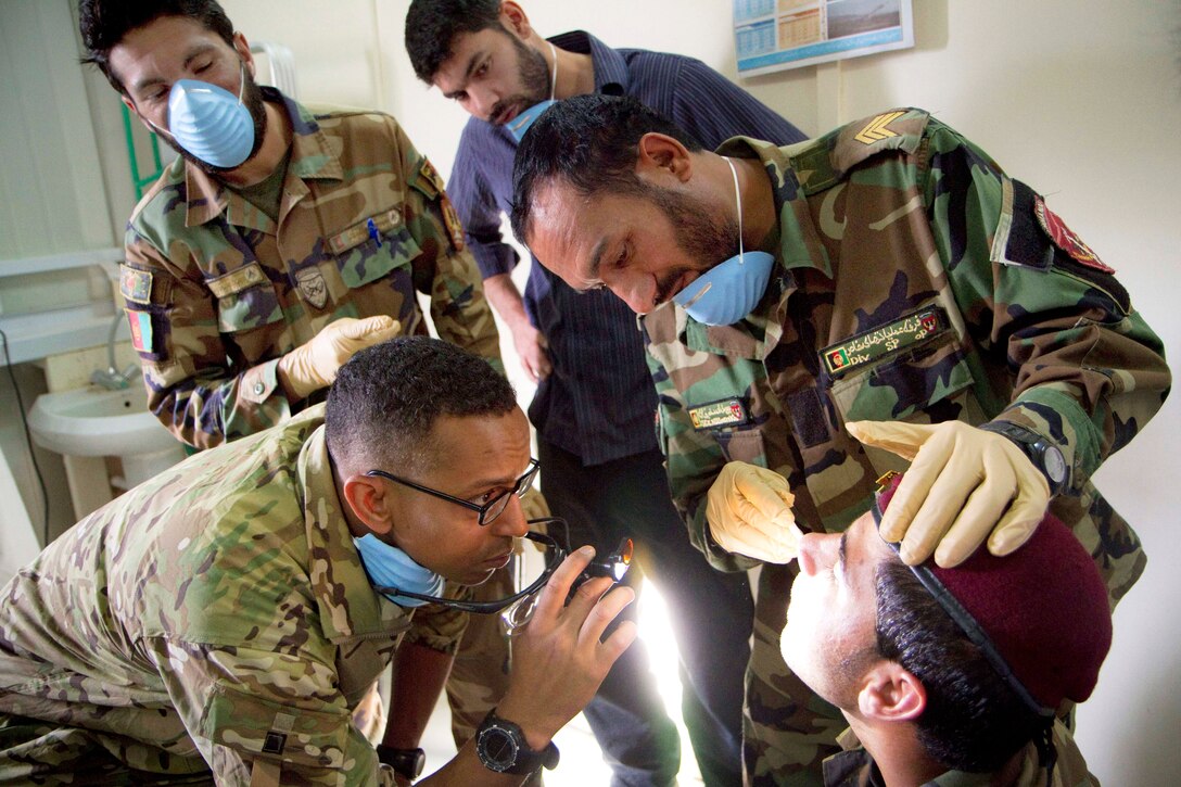 U.S. Army Capt. Abby Raymond, left, checks the work of an Afghan medic as he performs an oral exam on a commando during a basic dental class on Forward Operating Base Thunder in Paktya province, Afghanistan, July 21, 2013. Raymond, a dentist, is assigned to the 101st Airborne Division's 4th Brigade Combat Team.