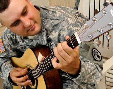 U.S. Army Sgt. Scott Black, a Warrior Transition Unit  healing warrior, plays his guitar at the WTU  at Fort Eustis, Va., July 11, 2013. Black is one of 30 Soldiers who have participated in the free “Music for Morale” program offered as part of the WTU’s healing program. (U.S. Air Force photo by Staff Sgt. Wesley Farnsworth/Released)  