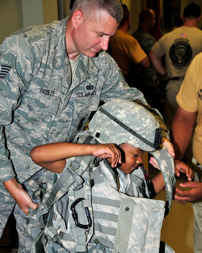 Tech. Sgt. John Fassler, 134 ARW Security Forces Journeyman, assists a young member of the Knoxville Police Department Youth Boot Camp in donning the "battle rattle" of an average airman during a base tour.  Members of the Knoxville Police Department Boot Camp visited McGhee Tyson ANG Base July 23 as part of the Phillip Moore Outreach Program in the local community.   (Air National Guard photo by Master Sgt. Kendra Owenby, 134 ARW Public Affairs)