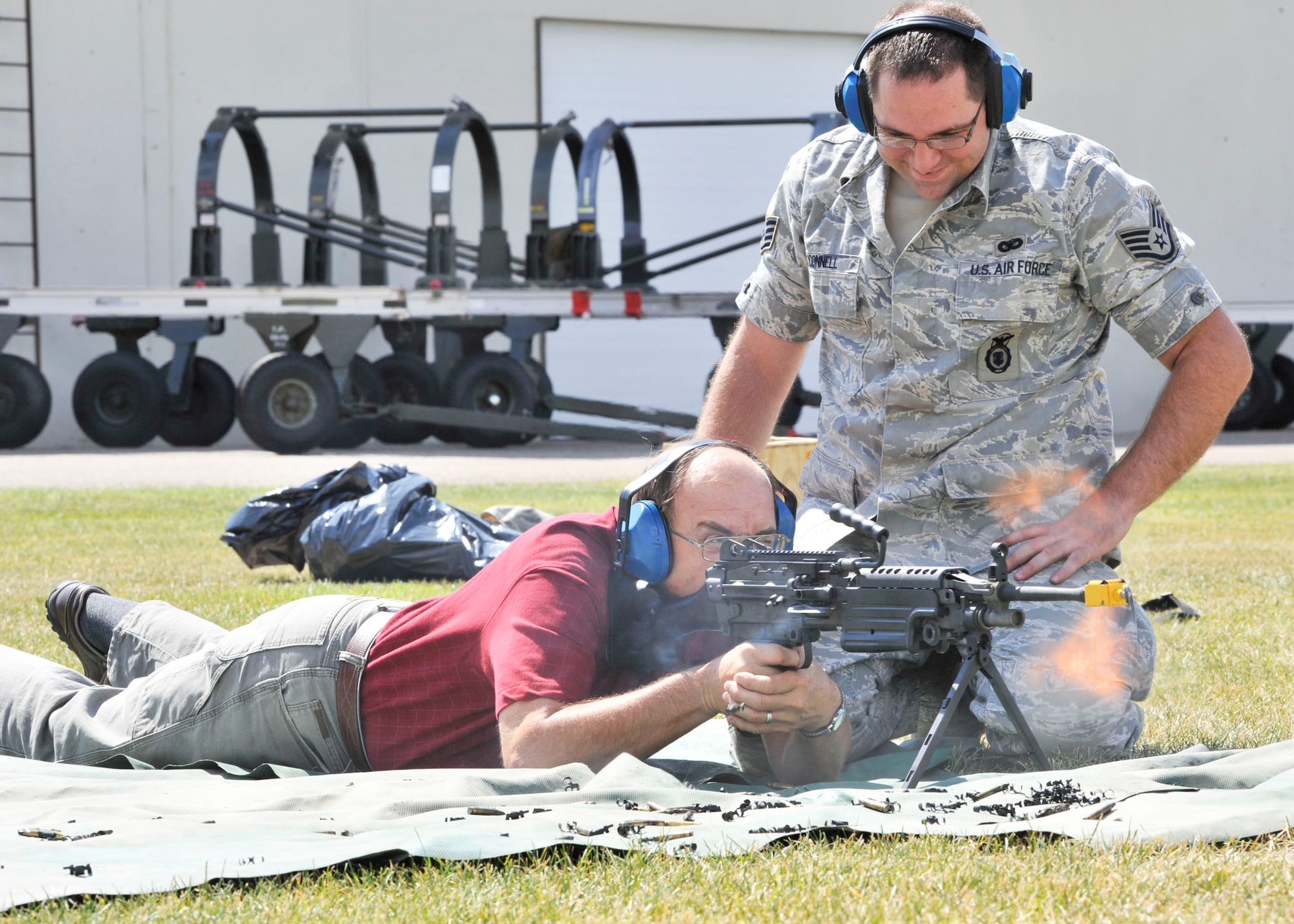 A family member fires blanks from an M60 machine gun while being observed by a member of the 120th Security Forces Squadron during the Montana Air National Guard Family Day on Aug. 11, 2012. (U.S. Air Force photo/Staff Sgt. John Turner)