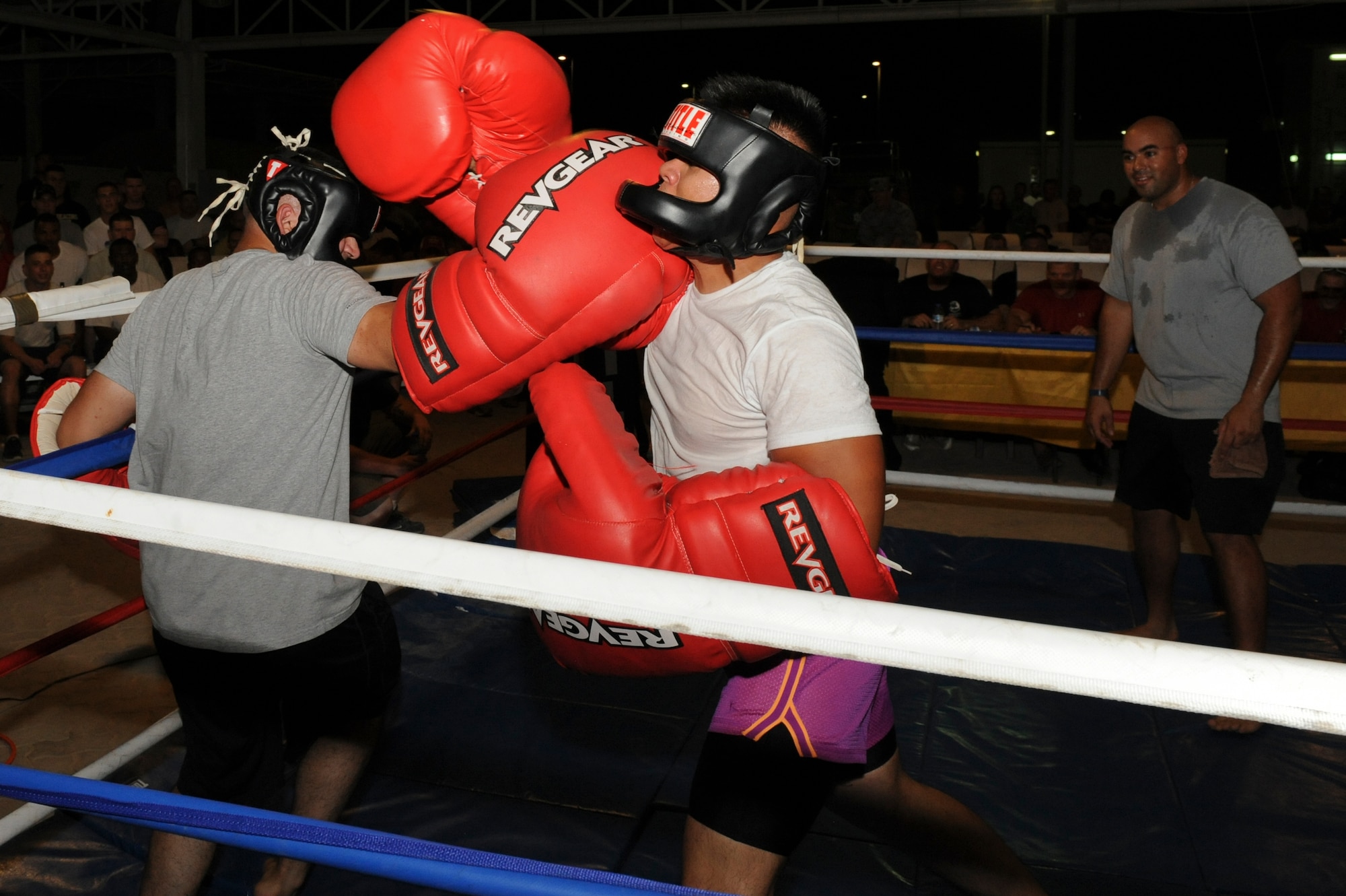 U.S. Air Force Airman 1st Class Carlos Sanchez, 380th Expeditionary Maintenance Squadron, hits U.S. Air Force Airman 1st Class Princeangelo Managu, 380th EMXS, with an uppercut during a big glove fight match at an undisclosed location in Southwest Asia July 19, 2013. The event was arranged for base personnel by several base agencies. (U.S. Air Force photo by Staff Sgt. Joshua J. Garcia)