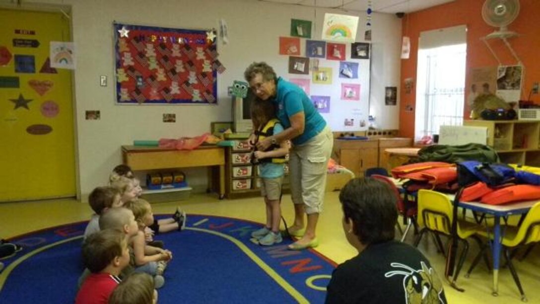 Water safety volunteer Pam VanderWeele shows a classroom of students the proper way to fit and fasten a life jacket.