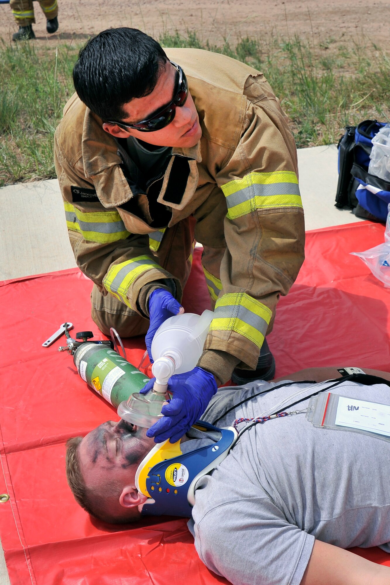 Airman 1st Class Edgardo Rodriguez-Hernandez assists a crash victim, an exercise role- player, in need of  medical transport during an emergency response exercise at the Air Force Academy July 22, 2013. Rodriguez-Hernandez is a firefighter with the Academy's 10th Civil Engineer Squadron. (U.S. Air Force photo/Sam Lee)