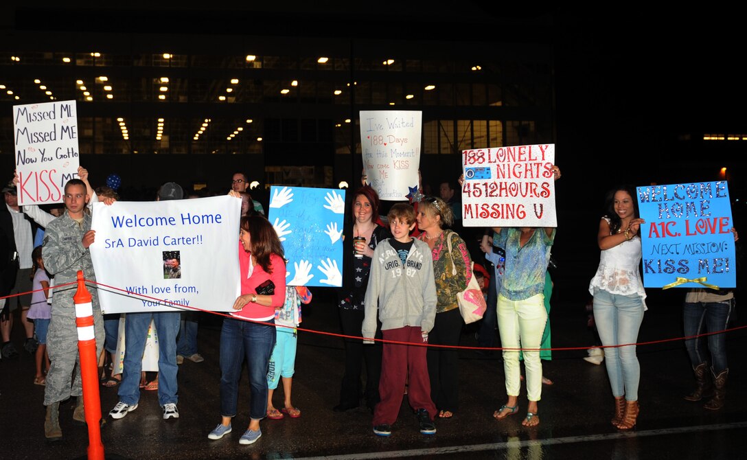 Family, friends and loved ones hold welcoming signs while anxiously awaiting the return of their Airmen from Southwest Asia during an event at the Pride Hangar on Ellsworth Air Force Base, S.D., July 26, 2013. The returning Airmen have been deployed since January, conducting B-1 bomber missions to deliver precision and non-precision strike capabilities to support military objectives in the U.S. Central Command area of responsibility.  (U.S. Air Force photo by Airman 1st Class Rebecca Imwalle/Released)