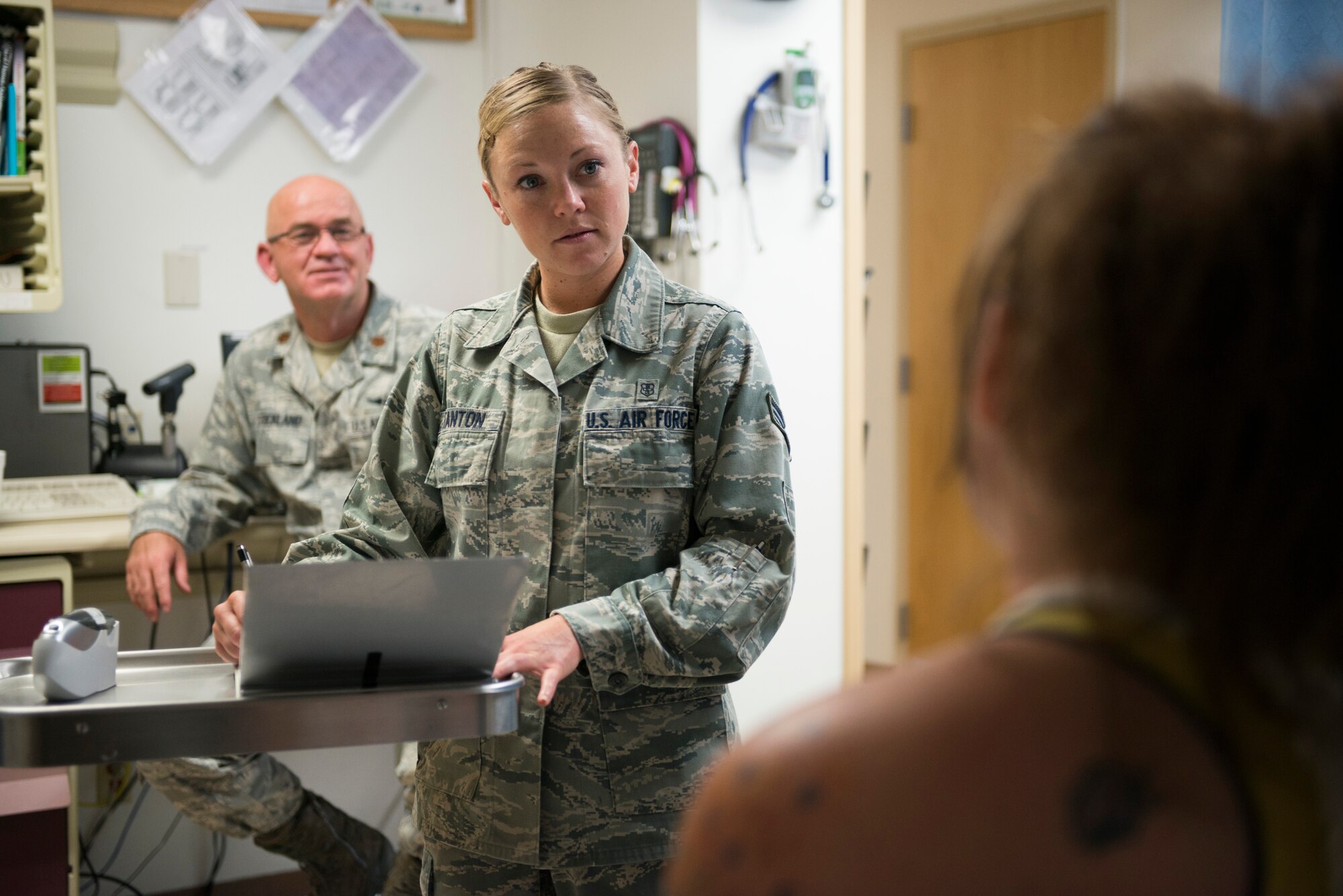 U.S. Air Force Senior Airman Megan Stanton (center), 366th Medical Operations Squadron medic, listens to a patient explain her condition while Maj. (Dr.) David Strickland (left), 366th MDOS physician, observes in the urgent care center at Mountain Home Air Force Base, Idaho, July 16, 2013. After Stanton's acceptance into the Air Force physician's assistant program, she has shadowed and been shadowed by UCC doctors to get a better idea of how to work with patients to discover their maladies. (U.S. Air Force photo/Tech. Sgt. Samuel Morse)