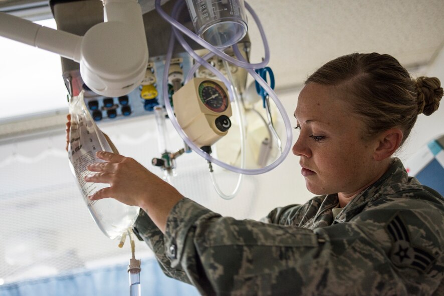 U.S. Air Force Senior Airman Megan Stanton, 366th Medical Operations Squadron medic, hangs a bag of IV fluid for a patient in the urgent care center at Mountain Home Air Force Base, Idaho, July 15, 2013. Stanton's regular duties revolve around caring for patients and assisting medical providers with treatment. (U.S. Air Force photo/Tech. Sgt. Samuel Morse)
