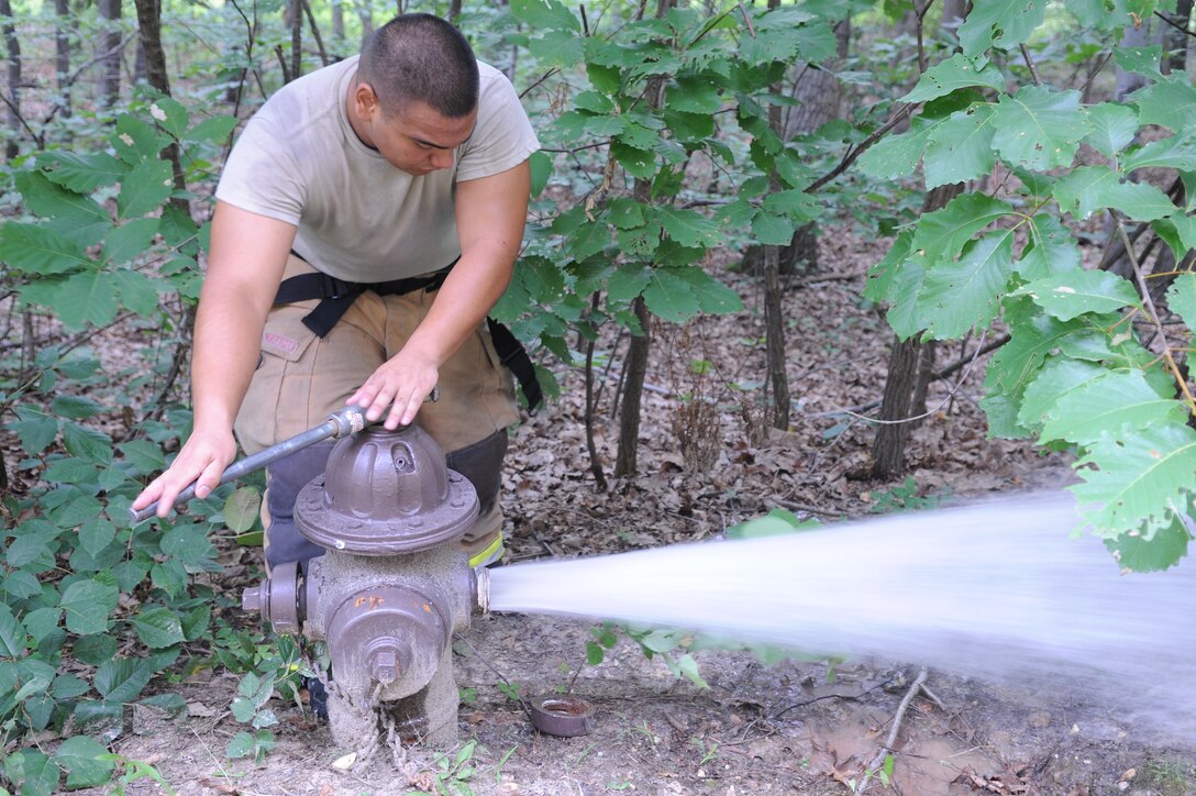 Airman 1st Class Patrick Gilbert, 11th Civil Engineer Squadron firefighter, inspects a fire hydrant behind the Base Exchange here at Joint Base Andrews, Md., July 24, 2013. Firemen familiarize themselves with the locations and functionality of fire hydrants around buildings and structures. (U.S. Air Force photo/Airman 1st Class Joshua R. M. Dewberry)