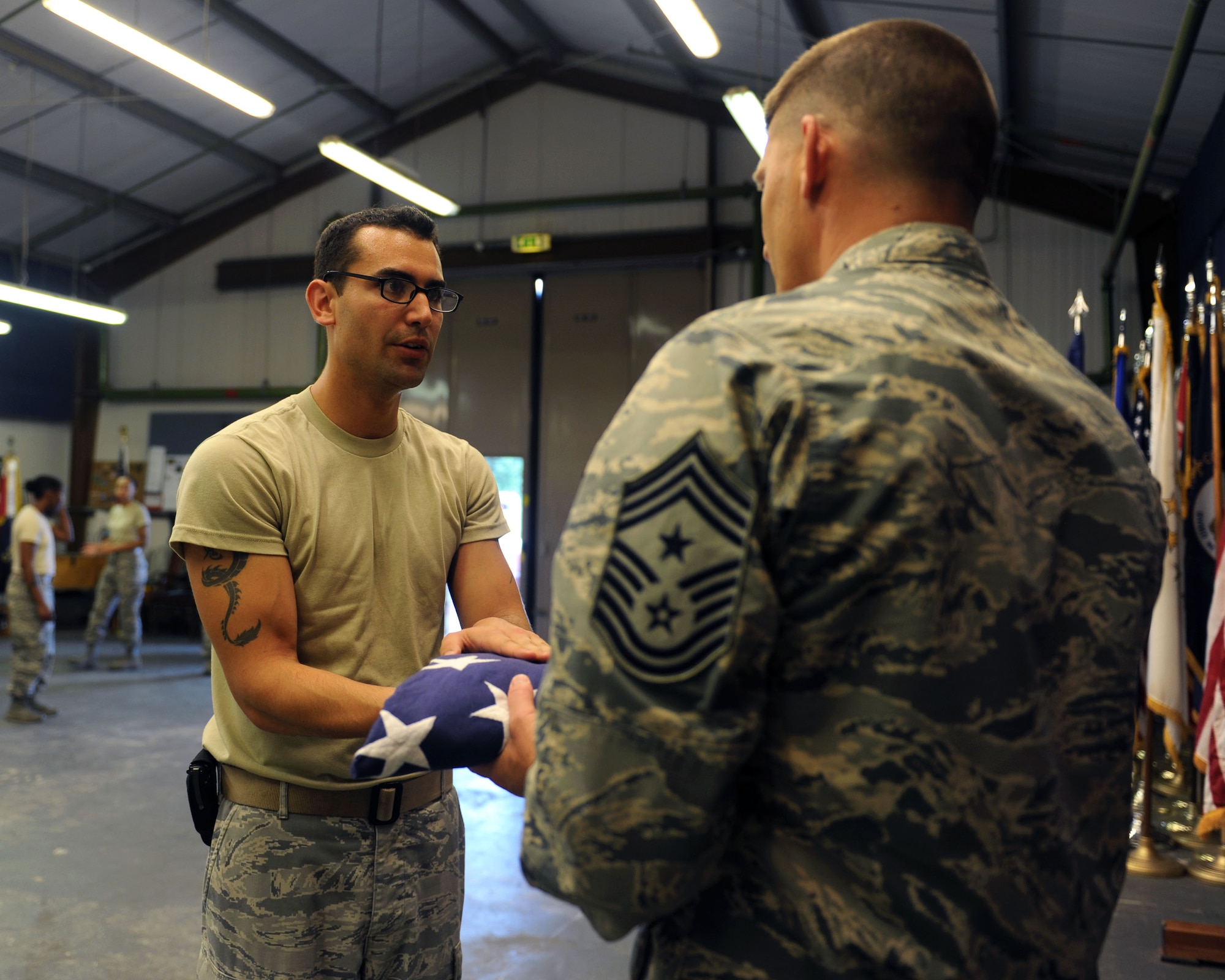 Staff Sgt. Edy Cruz Xuarez, 100th Civil Engineer Squadron electrical systems craftsman, presents the folded U.S. flag to Chief Master Sgt. Tracy Jones, 100th Air Refueling Wing command chief, who attended the honor guard practice session as part of the “Dirty Jobs” program July 24, 2013, on RAF Mildenhall, England. The “Dirty Jobs” program is a way for base leadership to experience the work Airmen do to make the RAF Mildenhall mission possible. Cruz presented the flag to Jones as if he were the surviving family member of a fallen Airman. (U.S. Air Force photo by Airman 1st Class Preston Webb/Released)