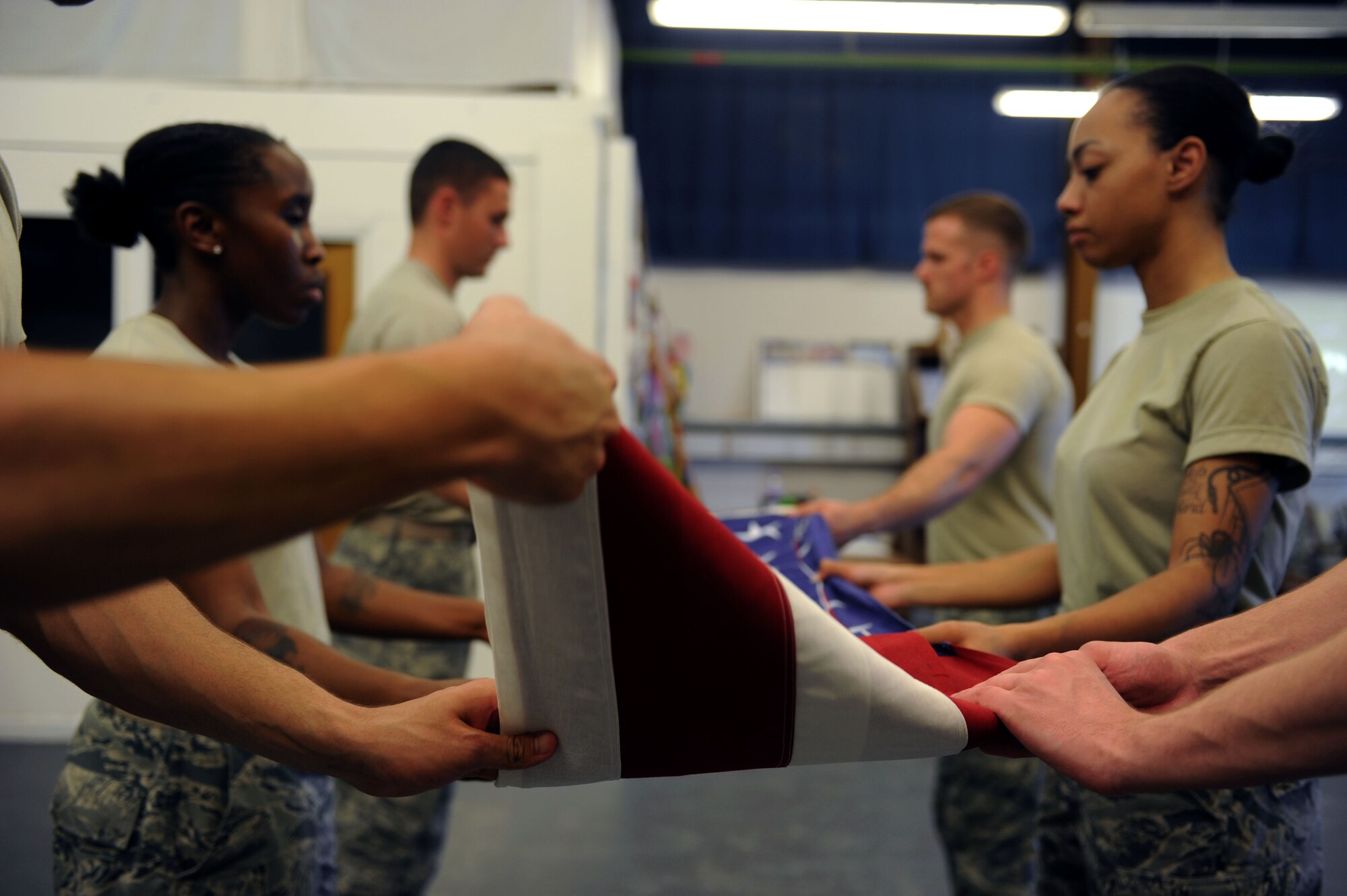 Team Mildenhall Honor Guard members fold the U.S. flag July 24, 2013, on RAF Mildenhall, England, while practicing funeral ceremony procedures. The flag is folded in honor of a fallen service member and presented to the family during the ceremony. (U.S. Air Force photo by Airman 1st Class Preston Webb/Released)