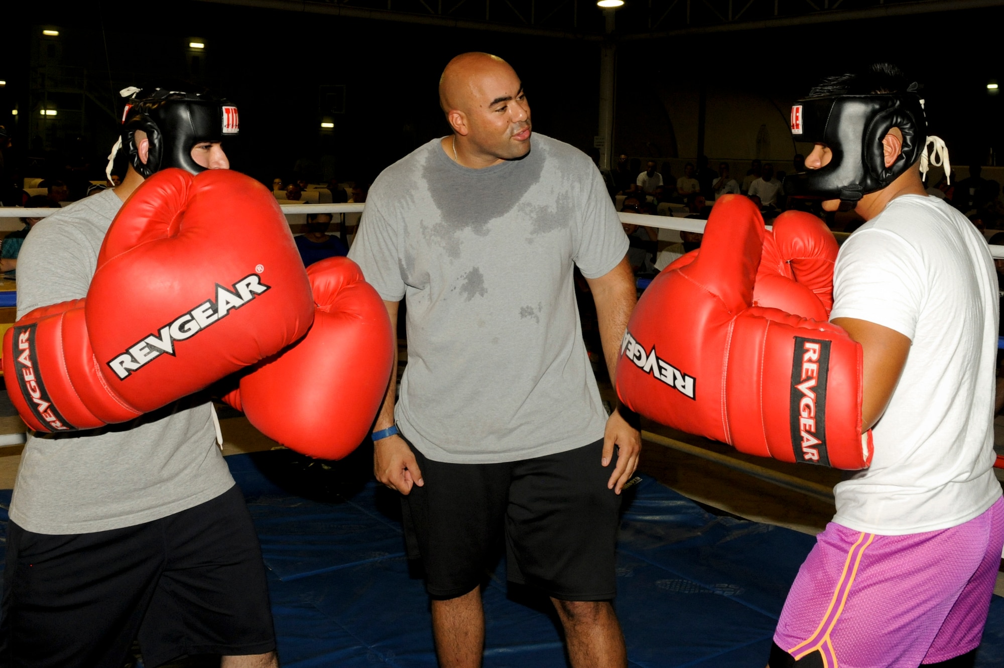 U.S. Air Force Staff Sgt. Roger Kemp, center, 380th Expeditionary Civil Engineer Squadron, tells two fighters the rules for the big boxing glove match, at an undisclosed location in Southwest Asia July 19, 2013. Kemp refereed all six matches for the evening. Kemp is deployed from Seymour Johnson Air Force Base, N.C. (U.S. Air Force photo by Staff Sgt. Joshua J. Garcia)