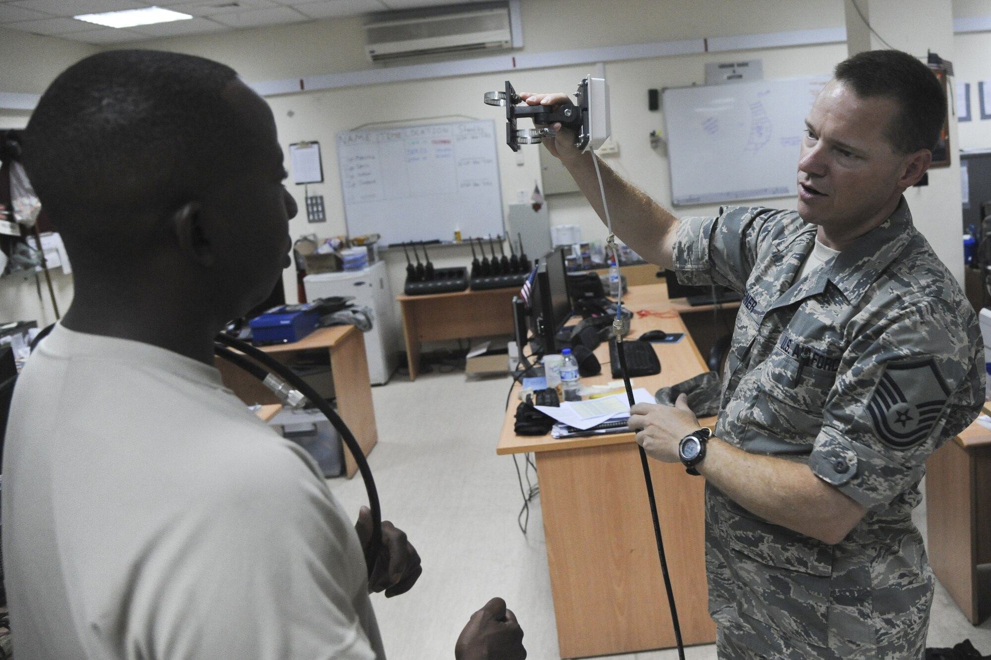 U.S. Air Force Staff Sgt. Jonathon Hobson, 380th Expeditionary Communications Squadron radio frequency transmissions supervisor, helps U.S. Air Force Master Sgt. Kevin Garner find the appropriate wire and tools to hang equipment at an undisclosed location in Southwest Asia July 23, 2013. The radio frequency shop assesses customer requirements and engineer solutions to specific locations, being mindful of radio frequency interference and hazardous radio frequency energy. Hobson calls Join Base Lewis-McChord, Wash., home and is deployed from Schriever Air Force Base, Colo. (U.S. Air Force photo by Senior Airman Jacob Morgan)