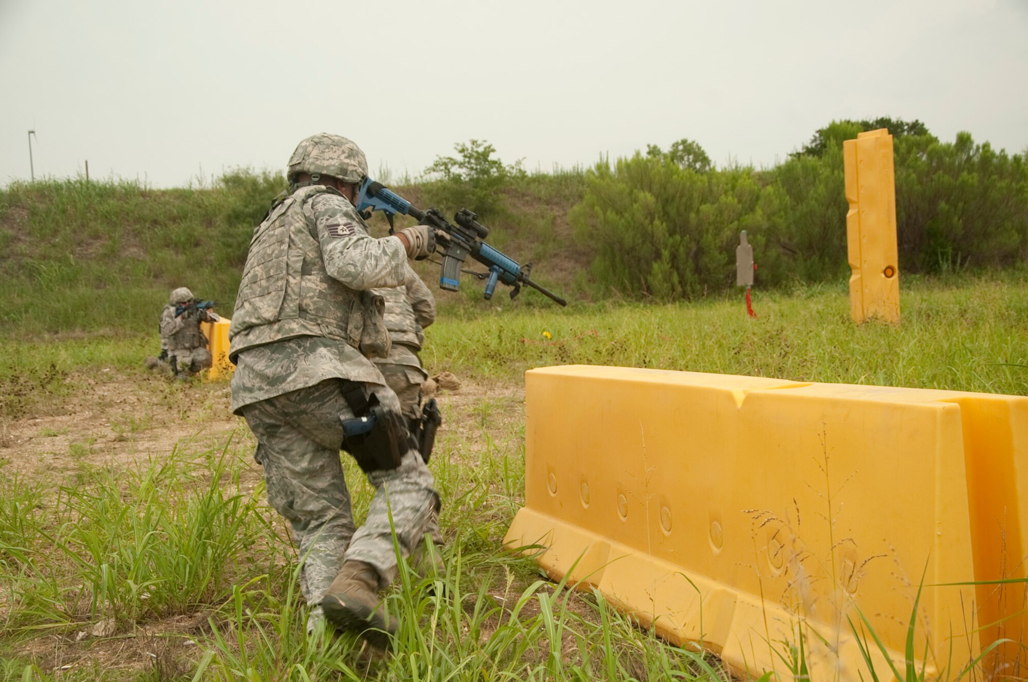 U.S. Air National Guard Master Sgt. Aubrey Beaver, 136th Security Forces Squadron yells out instructions to his fellow security forces members during a shoot and move exercise at Naval Air Station Fort Worth Joint Reserve Base, Texas, July 28, 2013. The exercise teaches basic maneuvers in an urban fire fight setting. (Air National Guard photo by Airman Cody Witsaman / released)