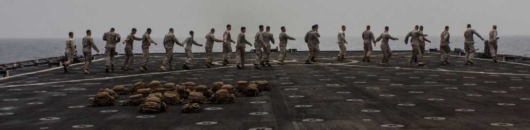 U.S. Marines assigned to 2nd Platoon, Company K, Battalion Landing Team 3/2, 26th Marine Expeditionary Unit (MEU), stretch before working out on the flight deck of the USS Carter Hall (LSD 50), at sea, July 25, 2013. The 26th MEU is a Marine Air-Ground Task Force forward-deployed to the U.S. 5th Fleet area of responsibility aboard the Kearsarge Amphibious Ready Group serving as a sea-based, expeditionary crisis response force capable of conducting amphibious operations across the full range of military operations. (U.S. Marine Corps photo by Cpl. Michael S. Lockett/Released)