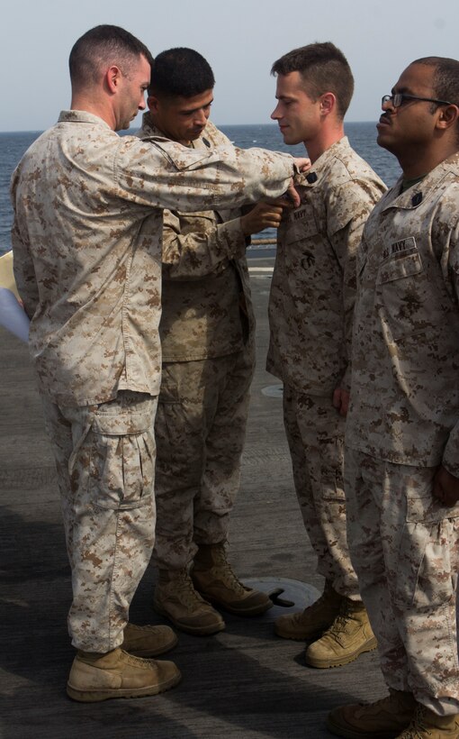 U.S. Marine Corps Capt. Raymond Kaster, left, Company K commanding officer, and U.S. Navy Hospital Corpsman 2nd Class Jimmey Gonzalez, assigned to the 26th Marine Expeditionary Unit (MEU), pin Hospital Corpsman 2nd Class Christopher Mullins, corspman from Statesboro, Ga., as he's awarded his enlisted Fleet Marine Force warfare specialist insignia and designation during a ceremony aboard the USS Carter Hall (LSD 50), at sea, July 26, 2013. The 26th MEU is a Marine Air-Ground Task Force forward-deployed to the U.S. 5th Fleet area of responsibility aboard the Kearsarge Amphibious Ready Group serving as a sea-based, expeditionary crisis response force capable of conducting amphibious operations across the full range of military operations. (U.S. Marine Corps photo by Cpl. Michael S. Lockett/Released)